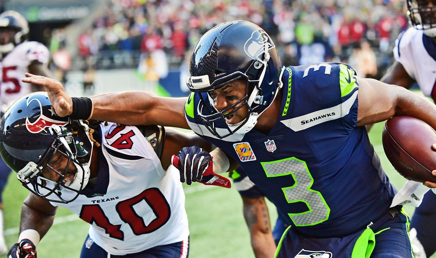 Seattle Seahawks quarterback Russell Wilson scrambles for good yardage before stiff-arming Houston Texans cornerback Marcus Williams to end the play in 2018.