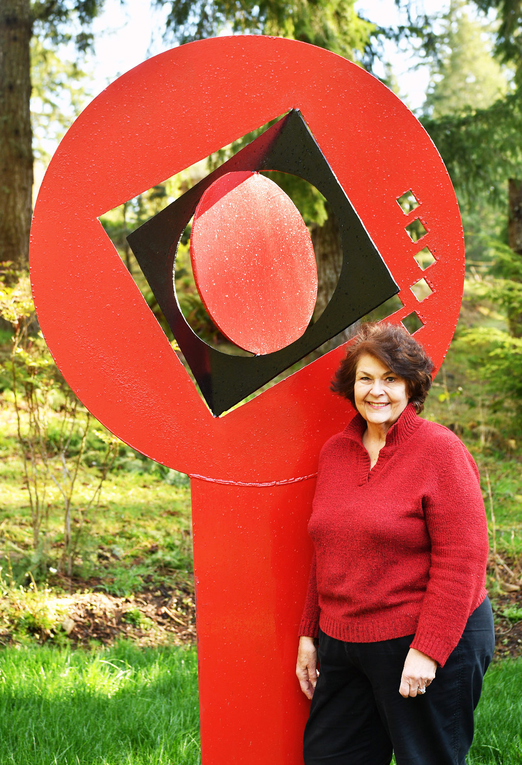 Rainier-area sculptor Myrna Orsini with her creation "The Sphere," a featured piece in her outside Monarch Sculpture Park.