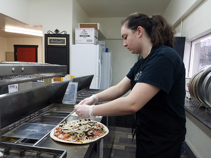 Karley Bornstein puts toppings on a pizza at Maverick's Pizza in Centralia. The store officially opened just a few days ago and has already become popular with local pizza lovers.