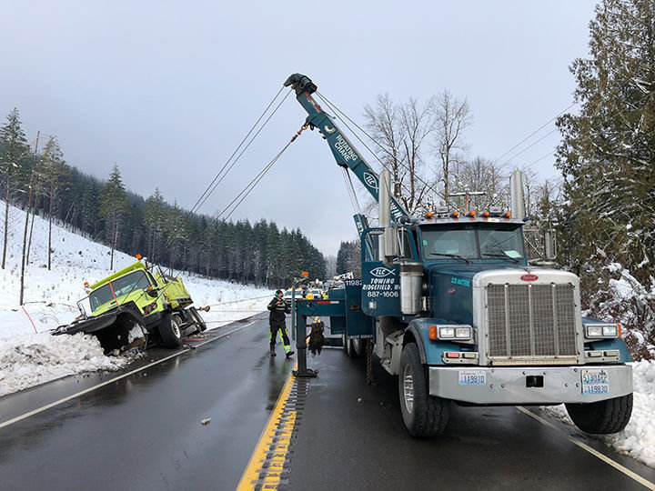 Tow crews work to pull a Washington State Department of Transportation snowplow out of a ditch between Morton and Mineral on state Route 7 on Feb. 13, 2019
