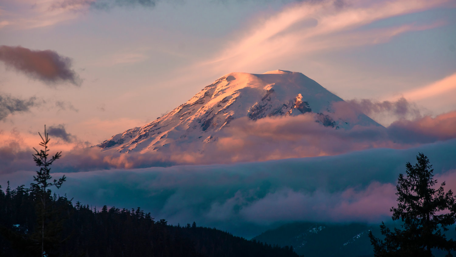 Clouds surround Mount Rainier at sunset.