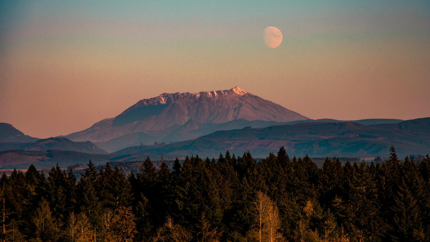 The moon rises above Mount St. Helens at sunset.