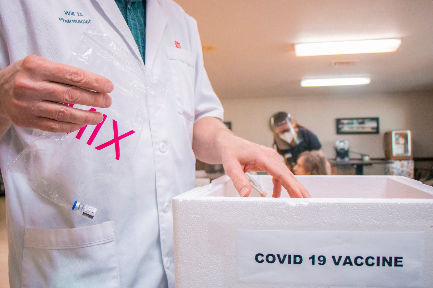 FILE PHOTO — Will Dix, a pharmacist with Walgreens for over 20 years, holds up a bag containing a Pfizer COVID-19 vaccine vile at Prestige Post-Acute and Rehab Center in January.
