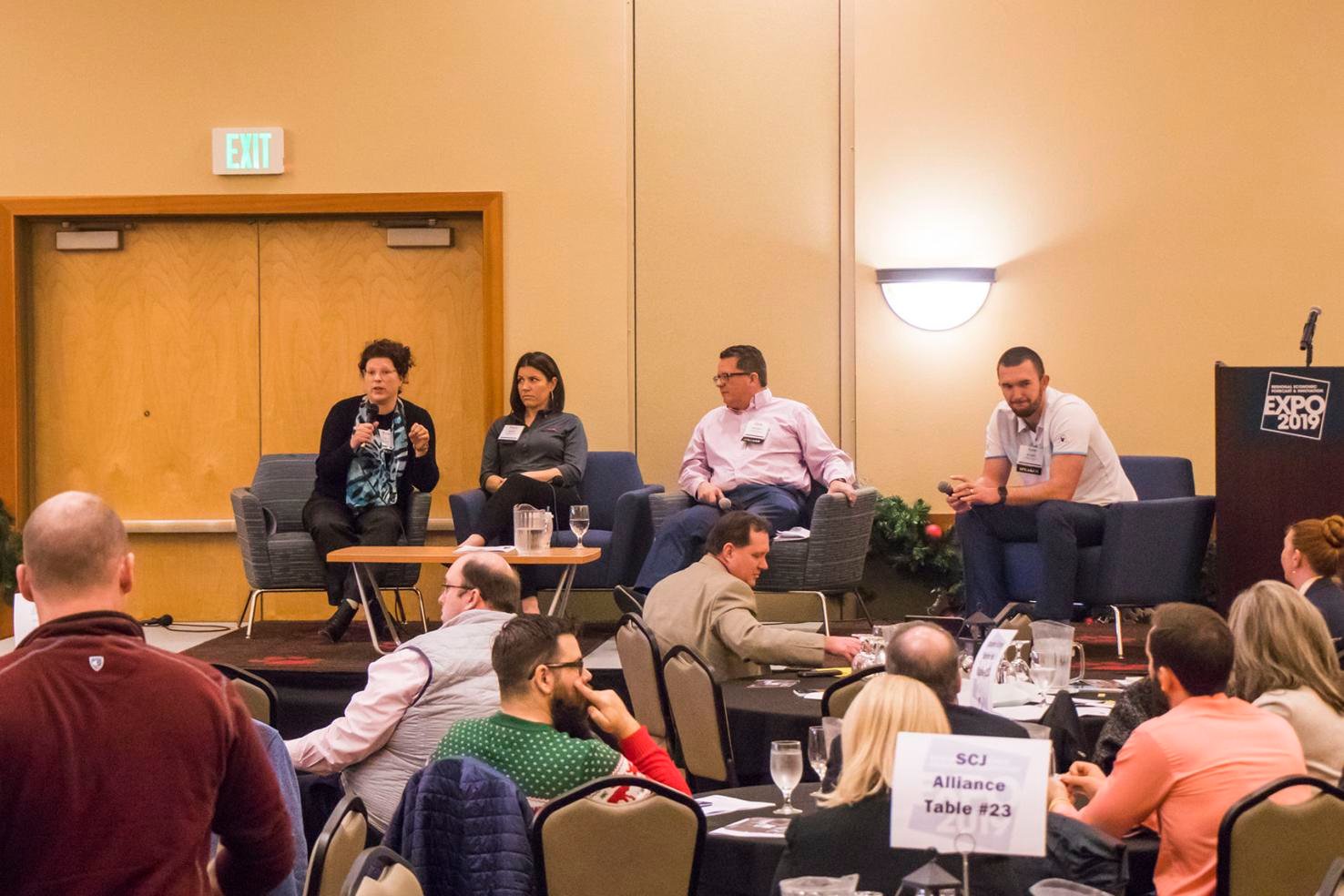 From left to right, Kate Cox, Tracie Schmitt, Chris Richardson, and Nate Burgher talk on stage during the Regional Economic Forecast & Innovation Expo hosted at Great Wolf Lodge in December 2019.