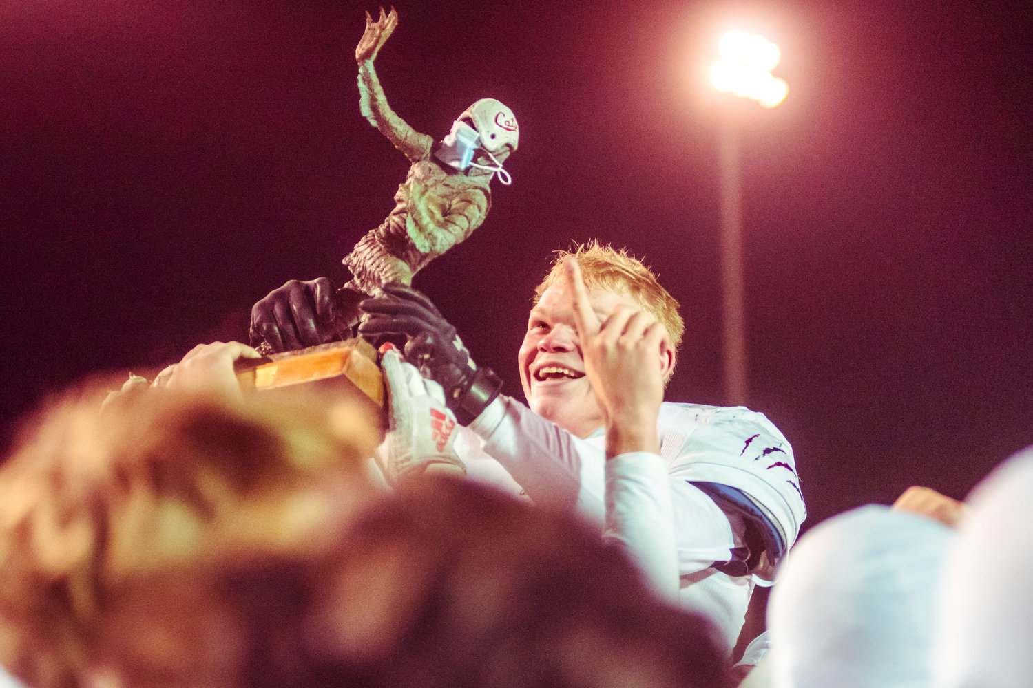 W.F. West's Evan Moon (53) smiles as he is lifted into the air by his teammates while holding up the Swamp Cup trophy following a game against Centralia Saturday night at Tiger Stadium.