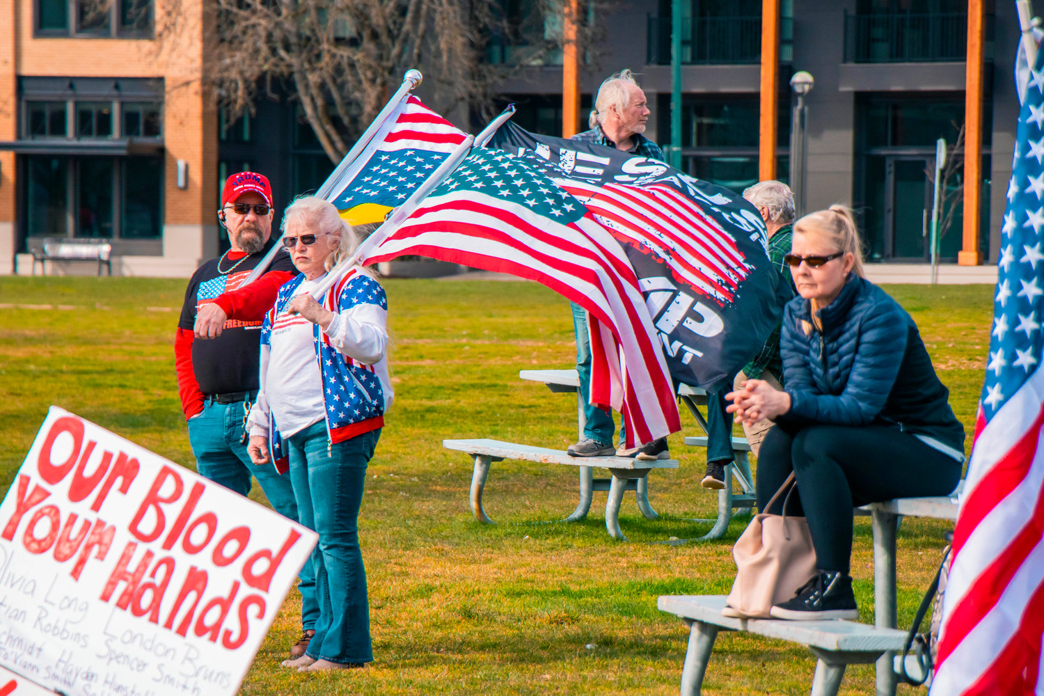 Flags are waved by attendees of a rally in support of reopening schools to full in-person learning near Capitol Lake in Olympia on Saturday.