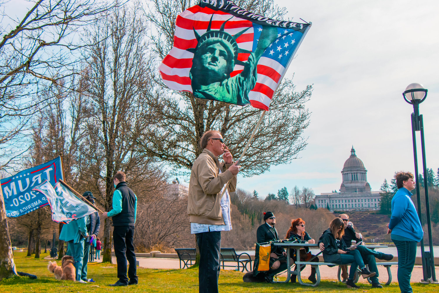 Flags are waved by attendees of a rally in support of reopening schools to full in-person learning near Capitol Lake in Olympia on Saturday.