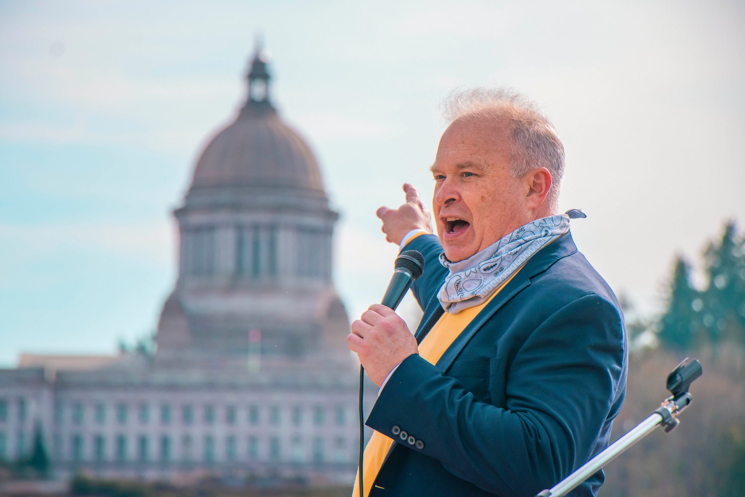 FILE PHOTO — State Rep. Jim Walsh points to the Washington State Capitol during a rally in support of bringing back in-person schooling.