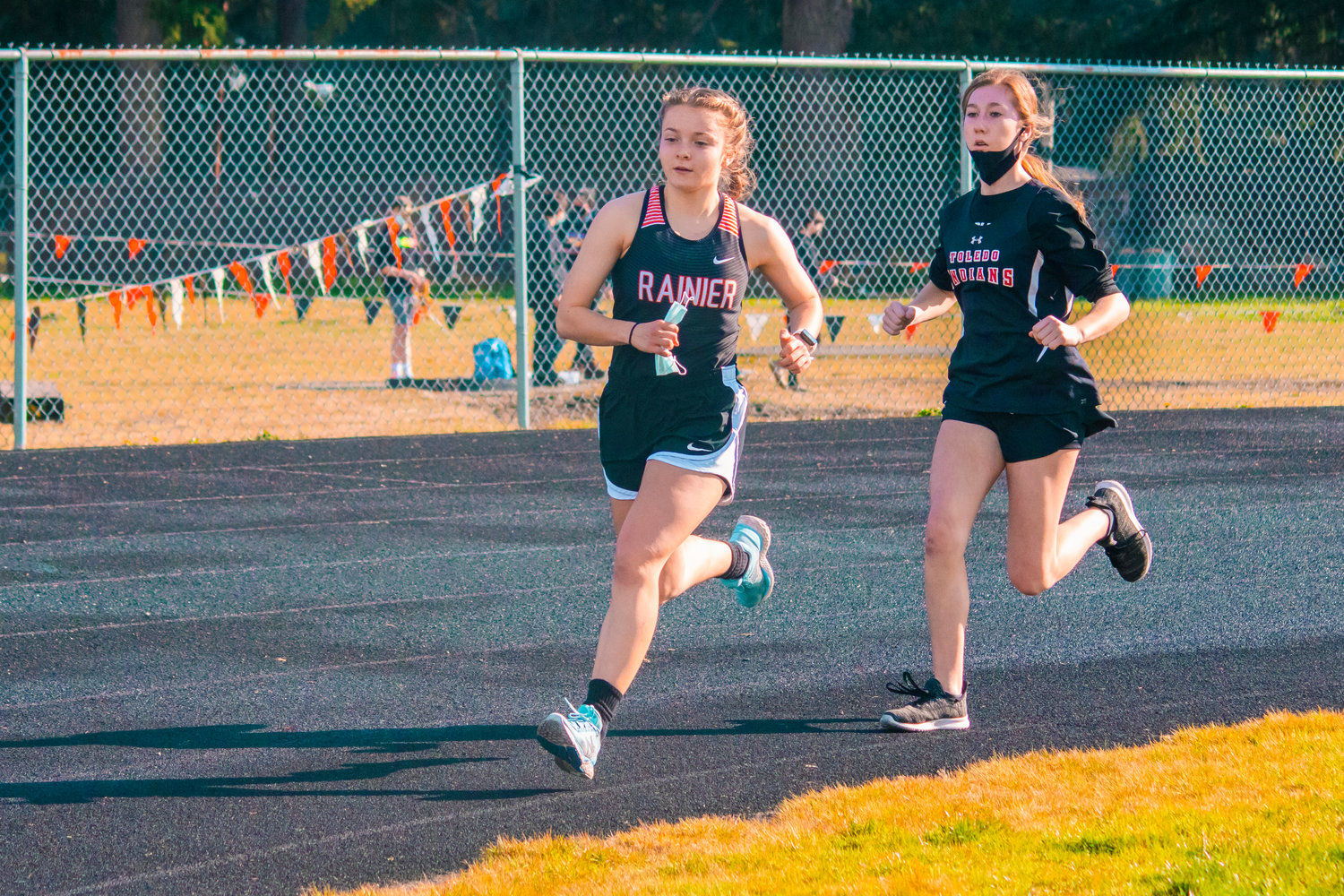 Rainier’s Selena Niemi and Toledo’s Karly Harris run during the girls 1600 on Thursday at Rainier High School.