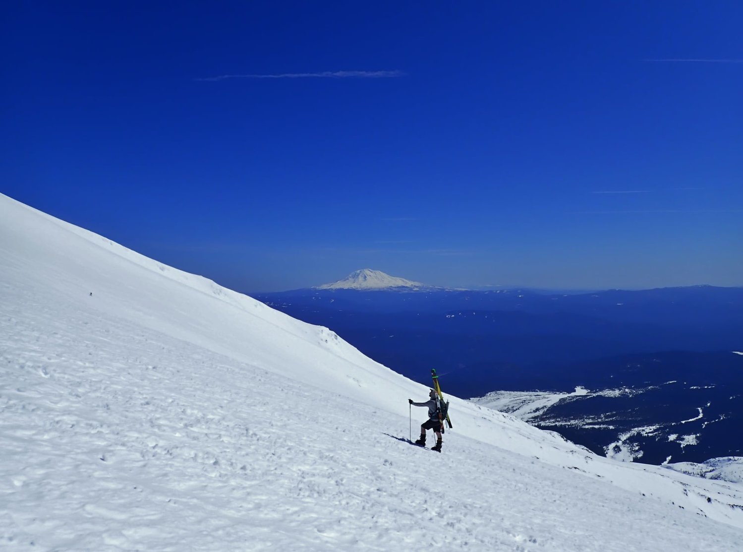 Mount Adams is seen in the background as a climber moves up the slopes of Mount St. Helens en route to the summit on March 31.