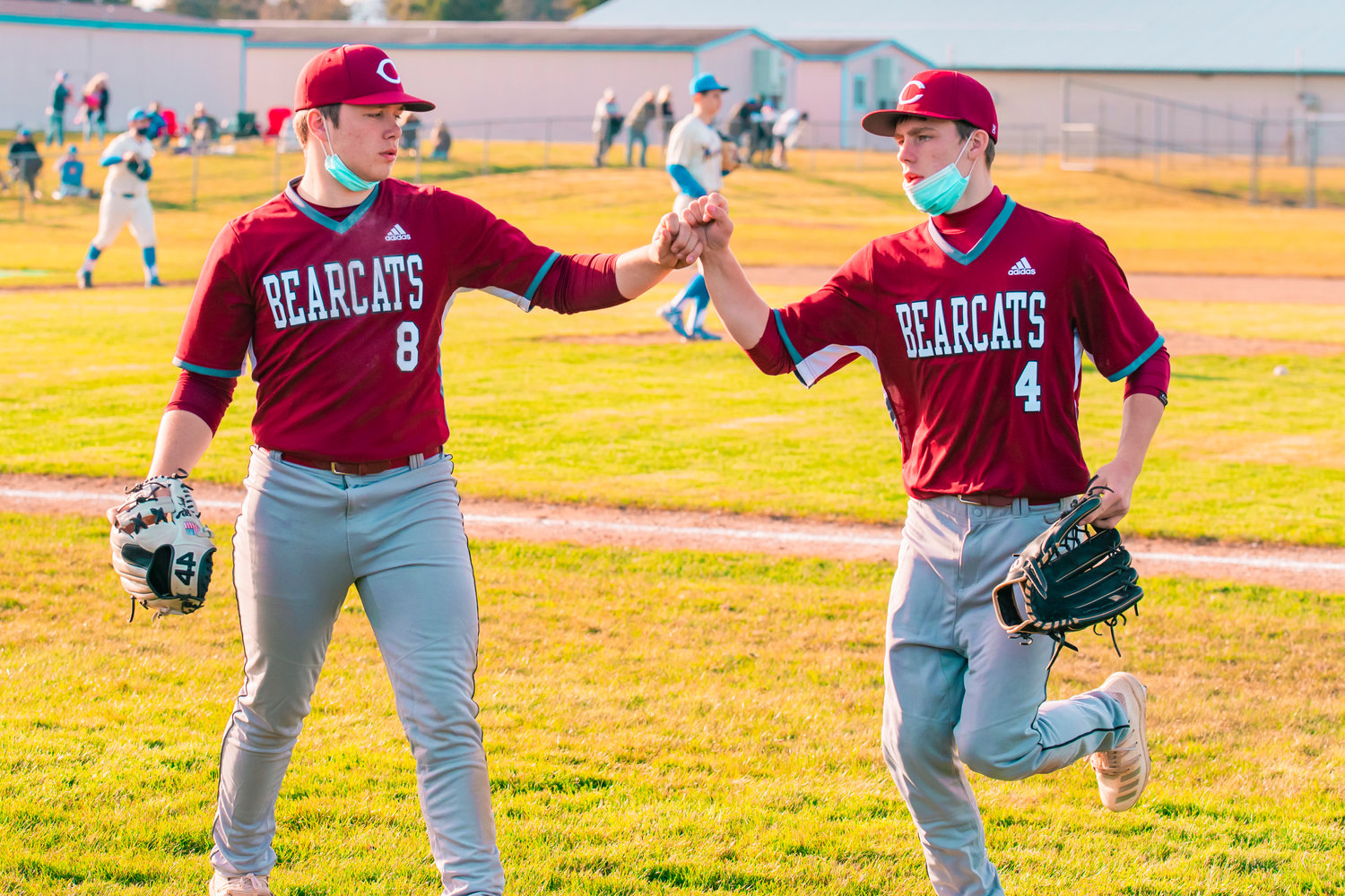 Bearcats’ pound fists as they retire an inning during a game against the Warriors in Rochester on Wednesday.