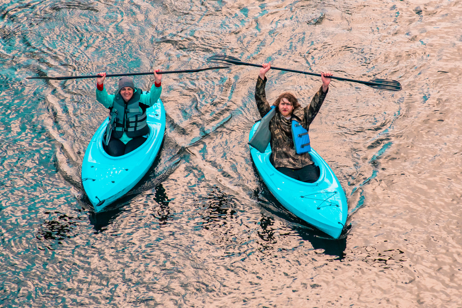 Andria Butterton and Michael Aughe raise their paddles as they make their way down the Chehalis River during the Pe Ell River Run on Saturday.