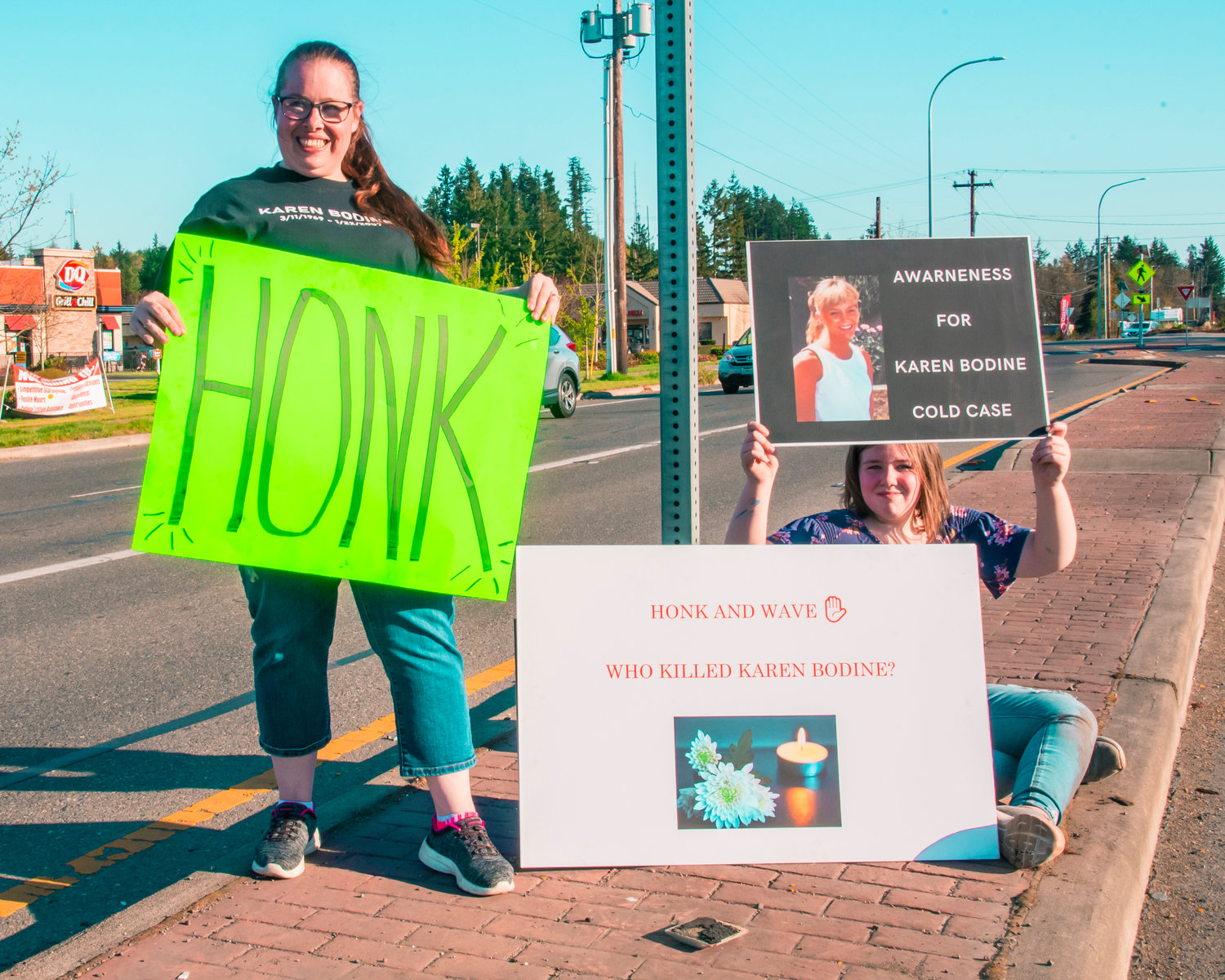 Heather Miller and Alexis Hartman hold signs during a honk-and-wave event to bring awareness for the cold case of Karen Bodine on Saturday in Grand Mound.