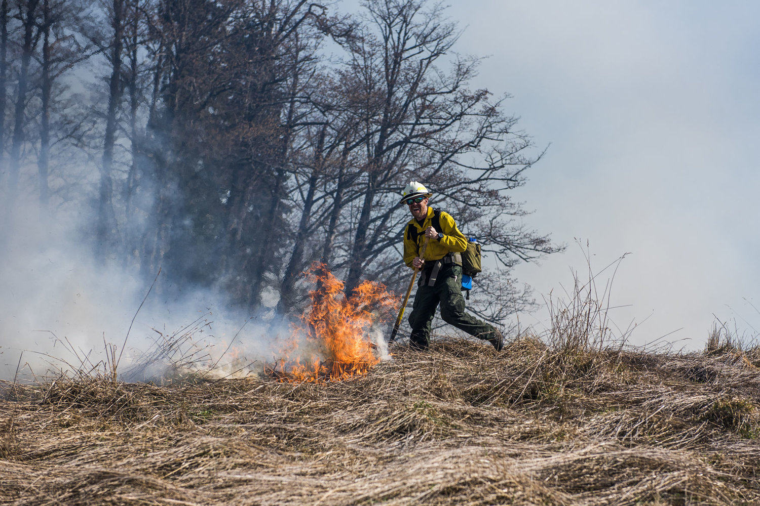 FILE PHOTO — A DNR wildlands firefighter yells to others as a flame rises through the brush near Ajlune road in 2018.