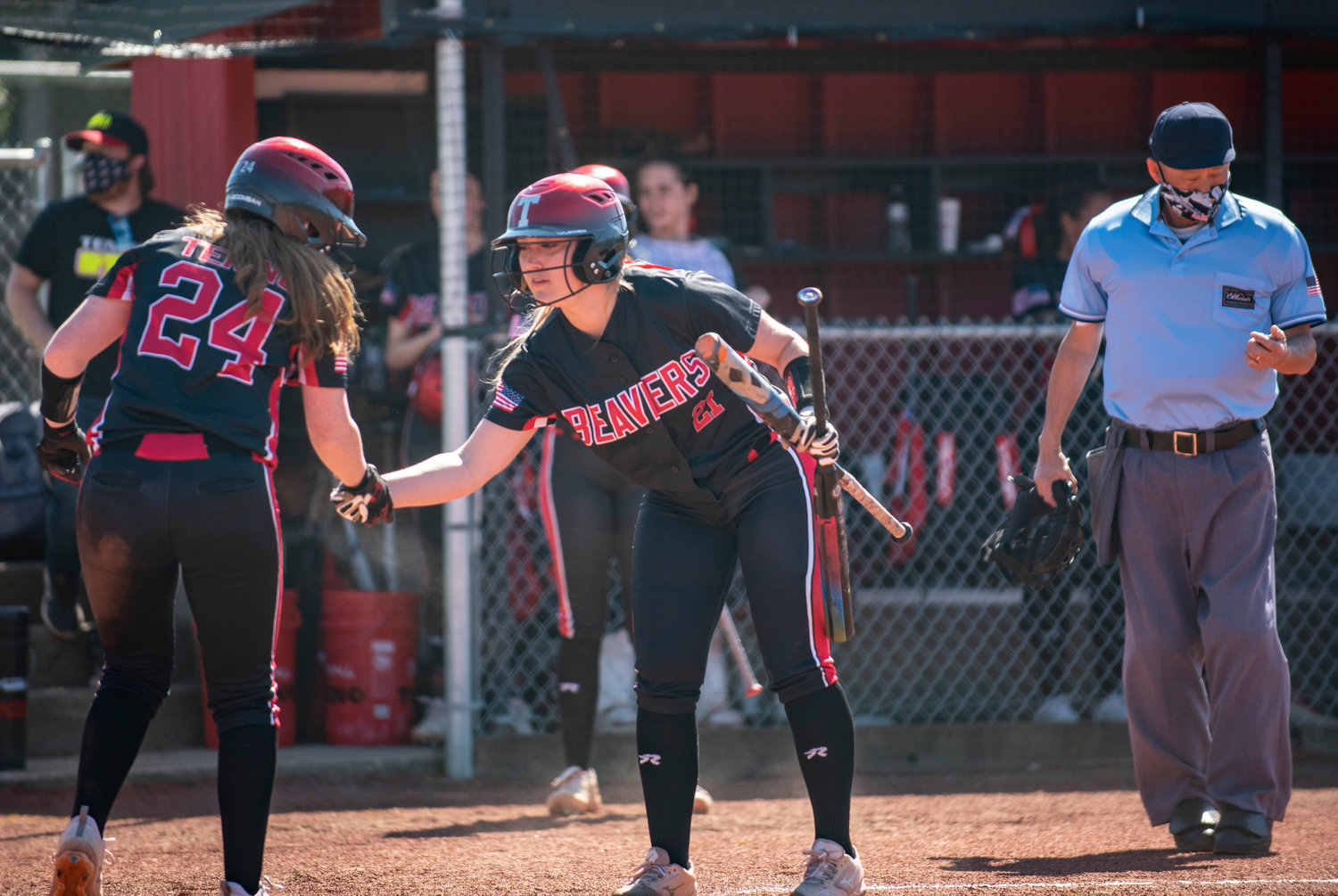 Tenino senior Cassie Cannon (21) congratulates junior Abby Severse (24) after Severse scores in the bottom of the first inning.