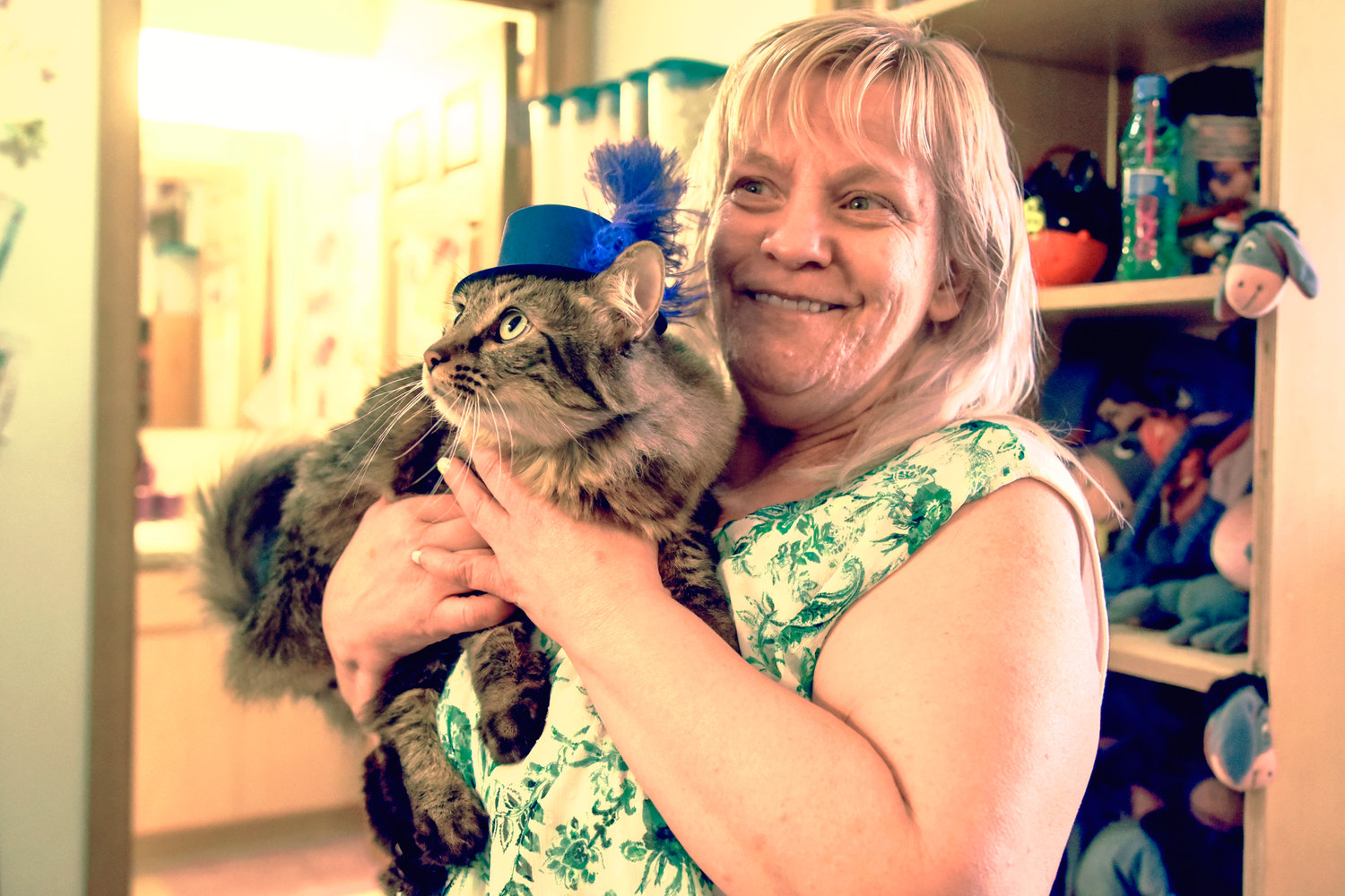 Debbie Nix smiles while holding her cat KJ as he sports a feathery hat in her Centralia residence.