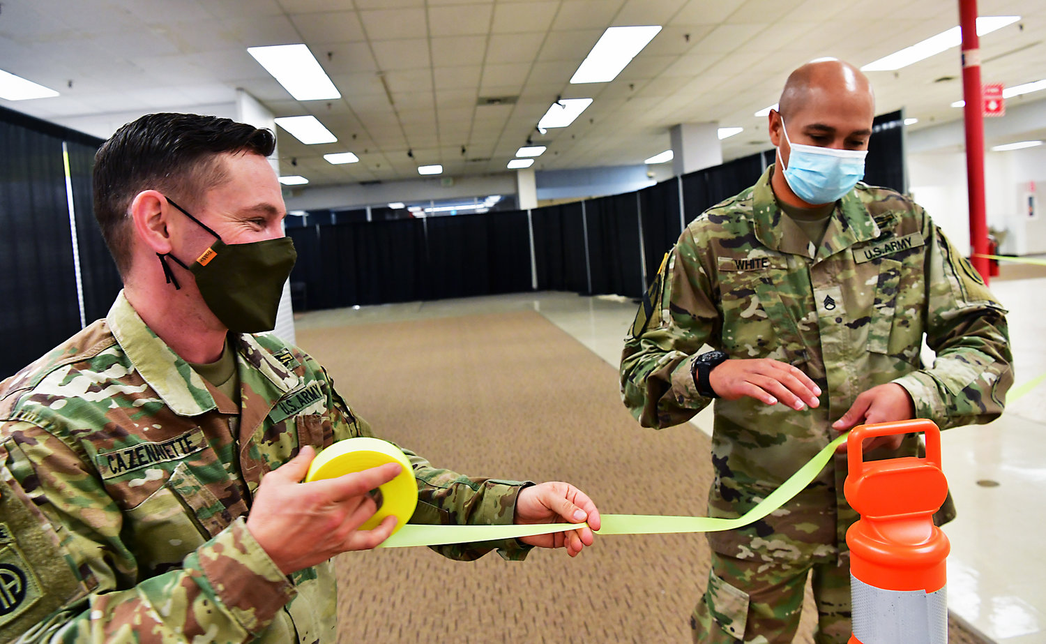 Washington Army National Guard Staff Sgt. Michael Cazenavette, left, and Staff Sgt. Earl White, place ribbon through cones on Tuesday, April, 27, to direct participants for Wednesday’s Public Walk-in Covid-19 Vaccine Clinic to be held in the former Sears location in the Lewis County Mall.