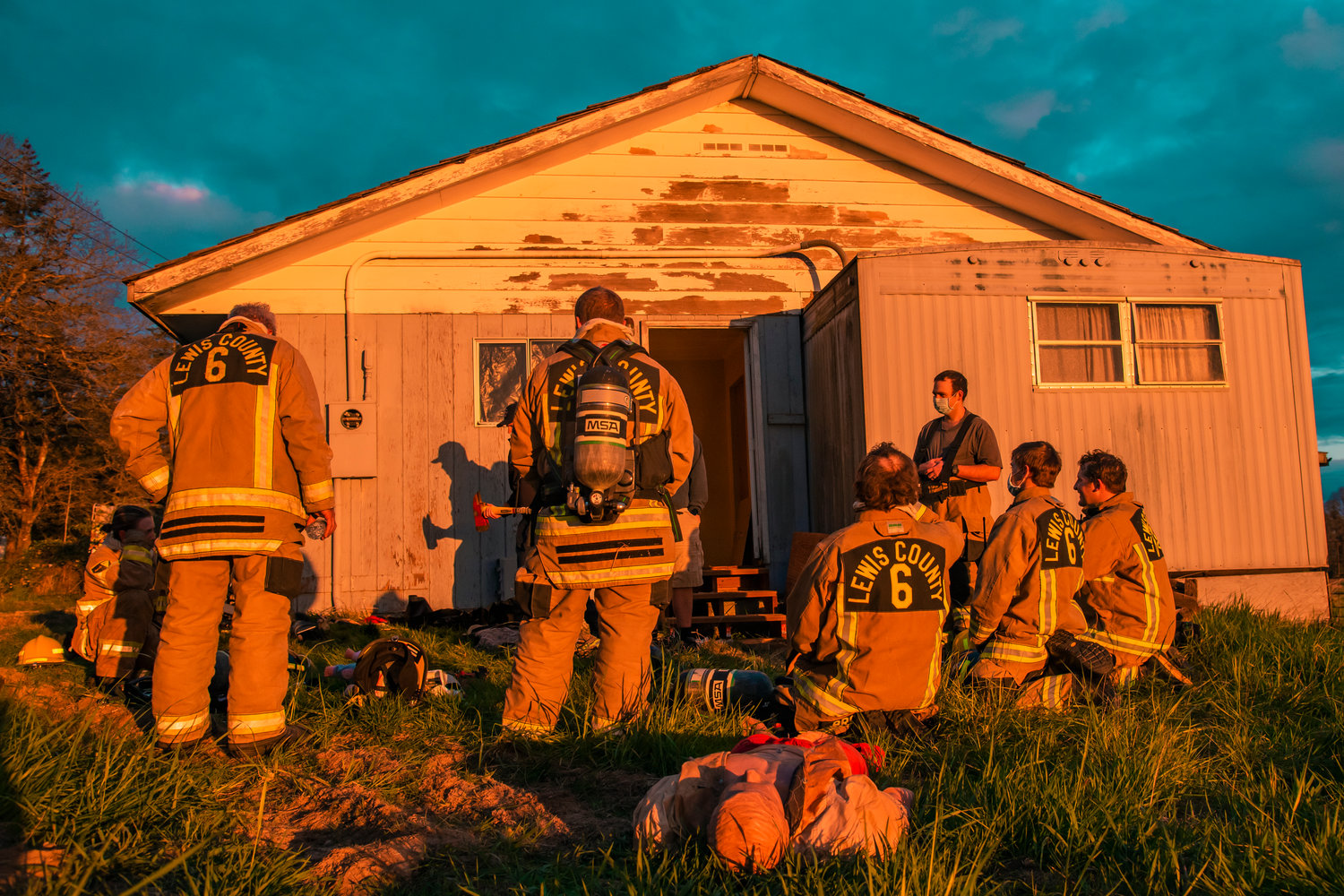 Lewis County Fire District 6 firefighters stand outside a home where they trained for search and rescue and officer-down exercises on Monday evening along Jackson Highway.