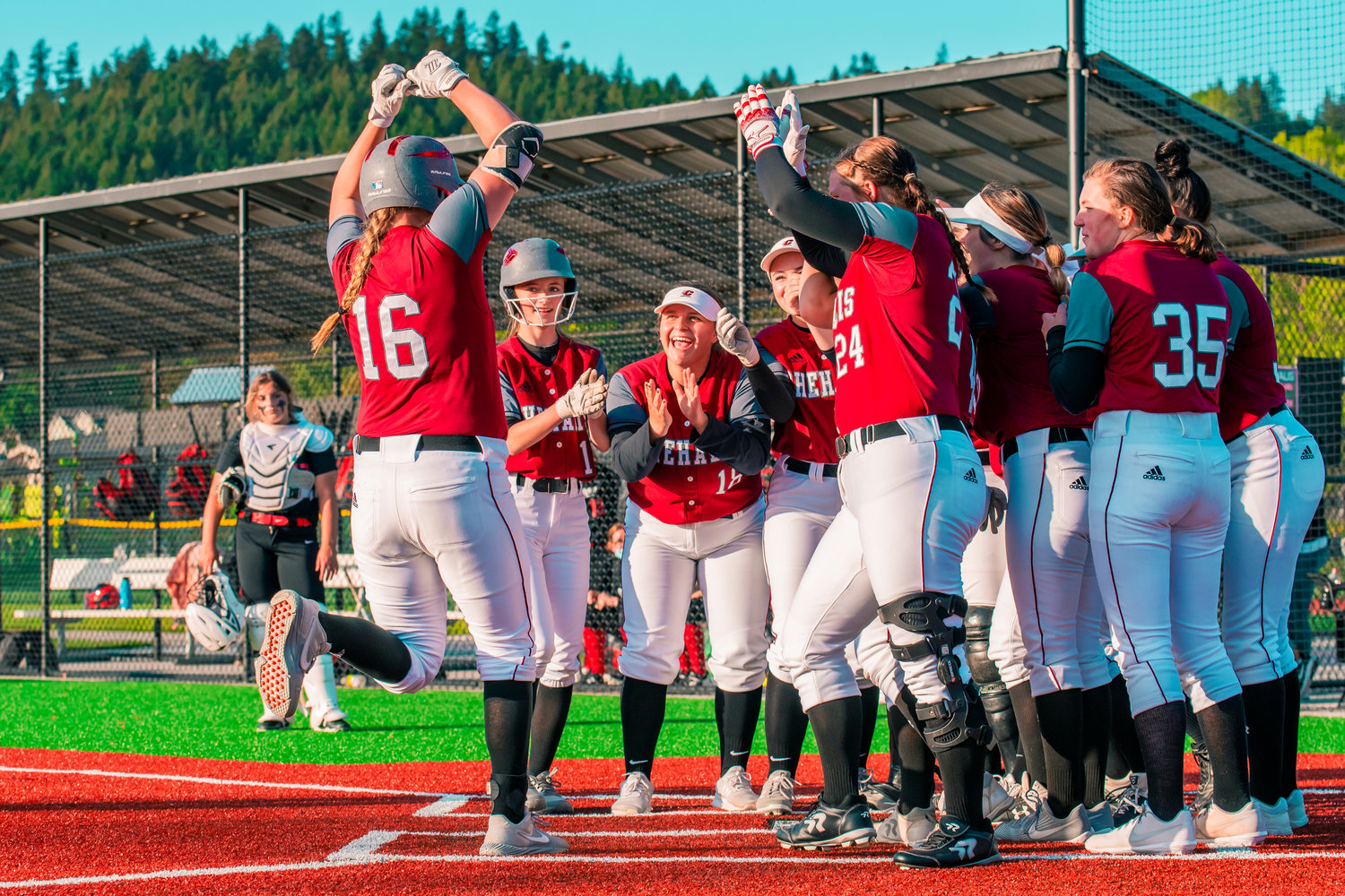 Kamy Dacus (16) is met at home plate by fellow players after knocking a ball out of the field for a homerun during a game against Shelton, Tuesday afternoon in Chehalis.