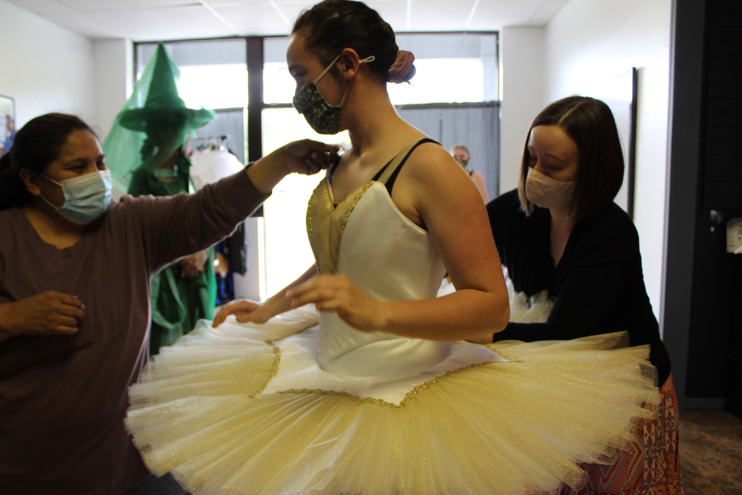 Marisol Williams and Emily Smith work together to fit one of the newly created pancake tutus on Brooke Larson, 16, who will dance the part of the Gold Jewel Fairy in "Sleeping Beauty Act III - Aurora's Wedding Tea" on May 16 and June 5.