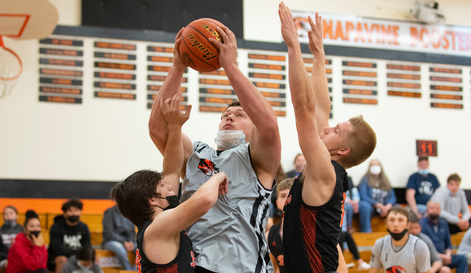 Napavine's Keith Olson takes the ball to the hoop in the paint against Rainier defenders.