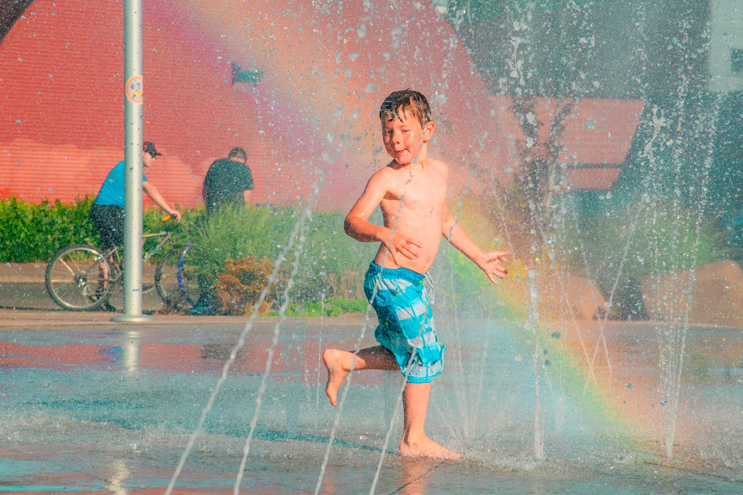 Tyrel Newkirk, 5, runs through streams of water to cool off at the Centralia splash park last month.