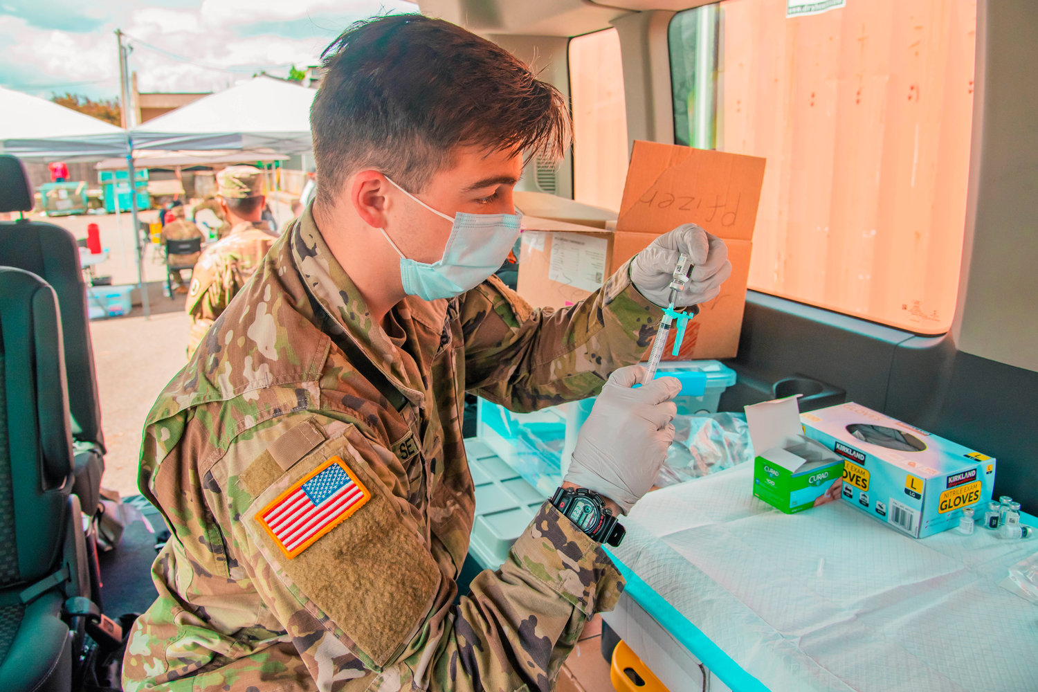 U.S. Army Specialist Settlecowski with the National Guard draws a dosage of the Johnson & Johnson coronavirus vaccine from a vial during a clinic held at the Market Street Ace in Chehalis.