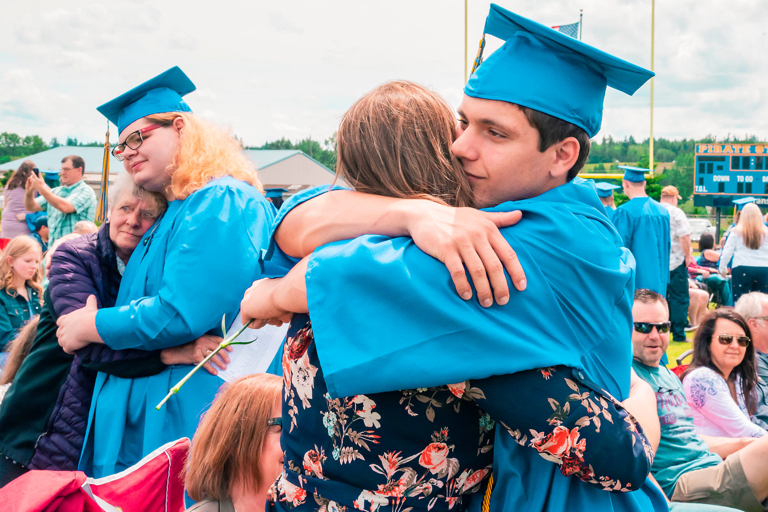FILE PHOTO — Graduates greet family with hugs and flowers during a graduation ceremony at Adna High School.