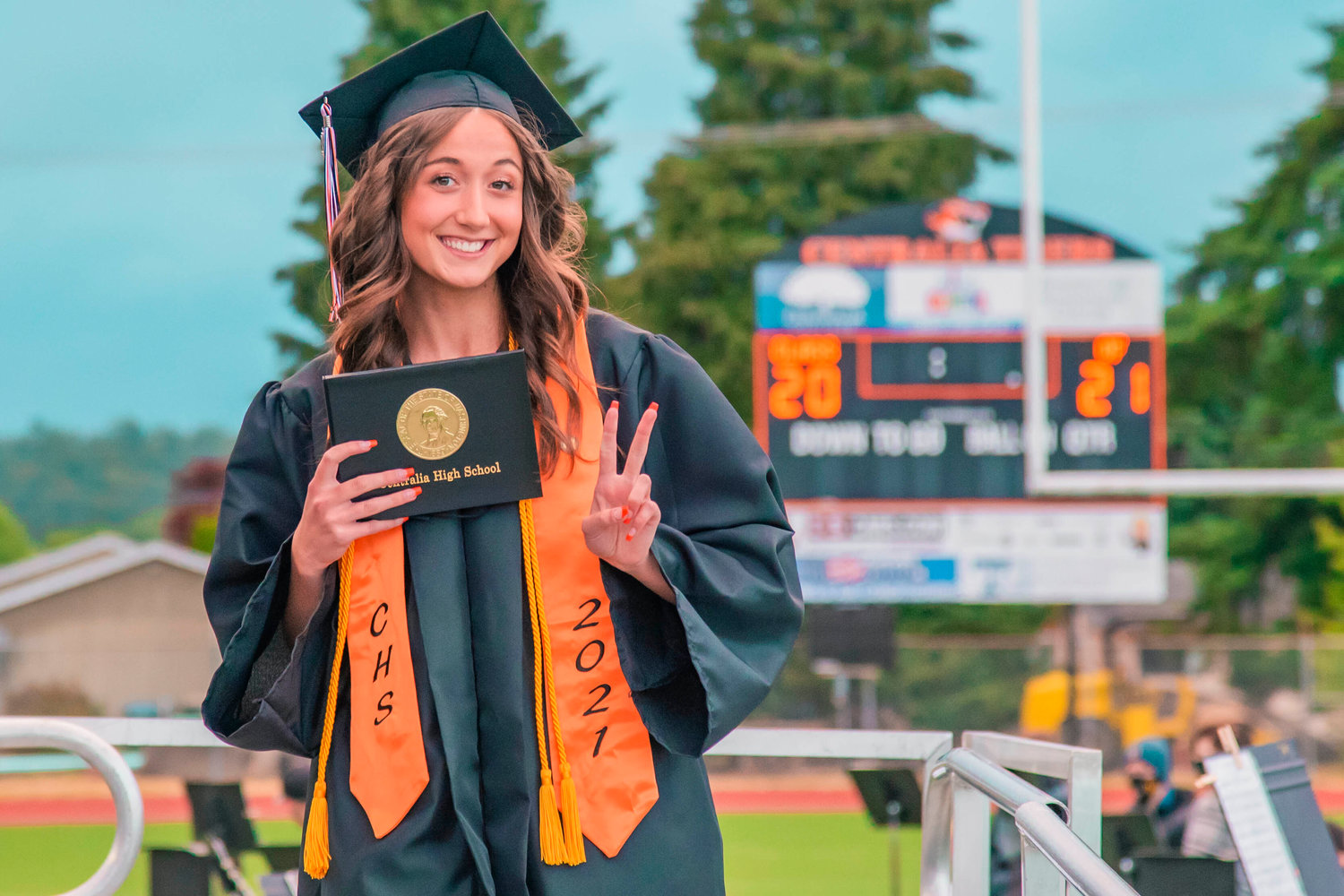 Faith Waterfield smiles and holds up her diploma during a graduation ceremony at Tiger Stadium Friday night in Centralia.