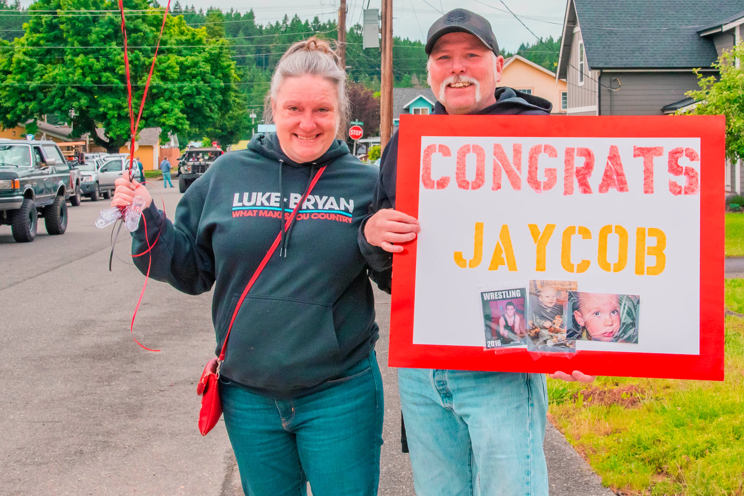 Sarah White and Billy Shivvers hold up a sign for Tenino graduate Jaycob White during a parade on Friday.