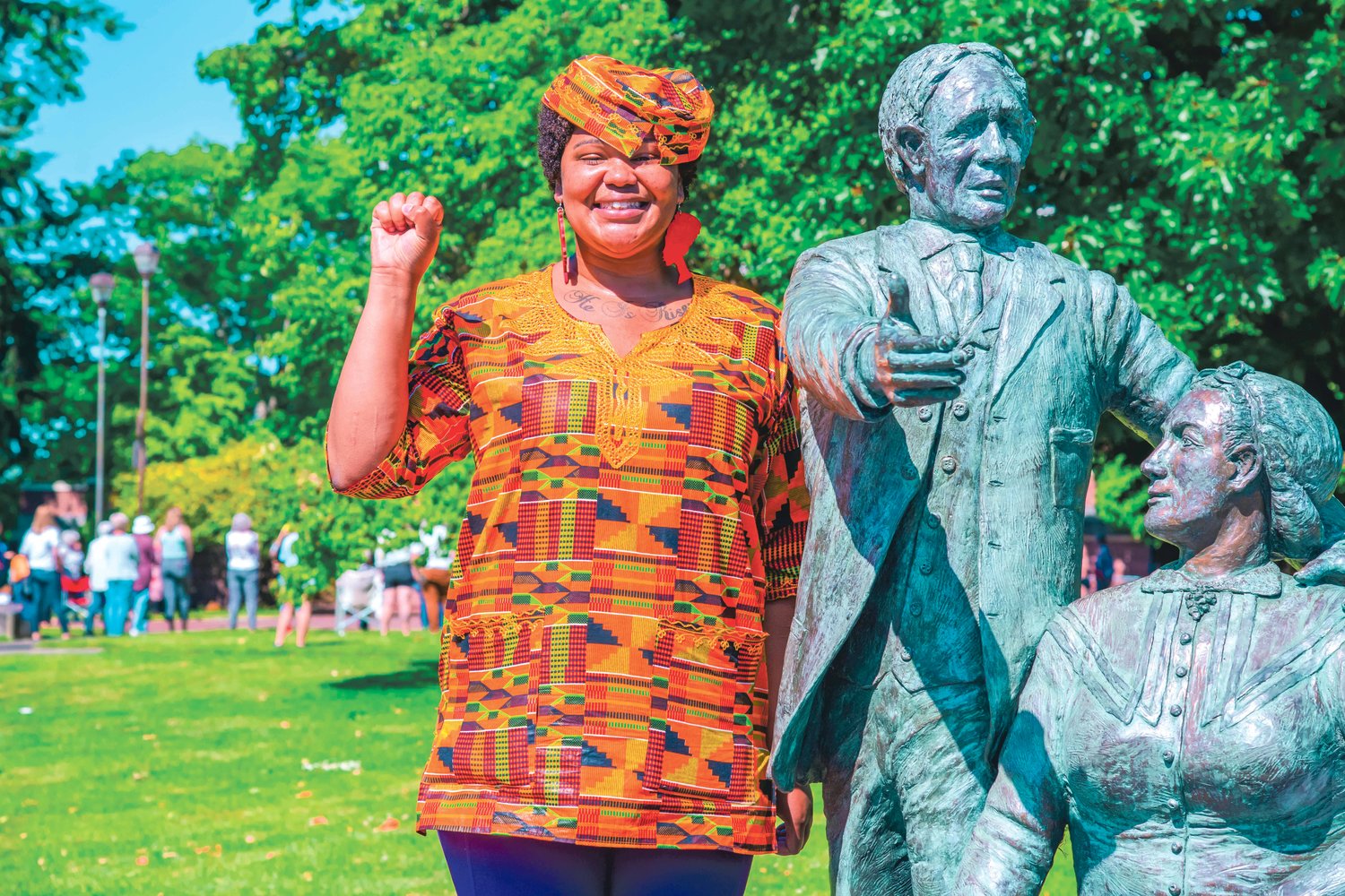 DE'Erica Waggener smiles and holds up her fist while posing next to the statue at George Washington Park during Juneteenth celebrations in Centralia on Saturday.