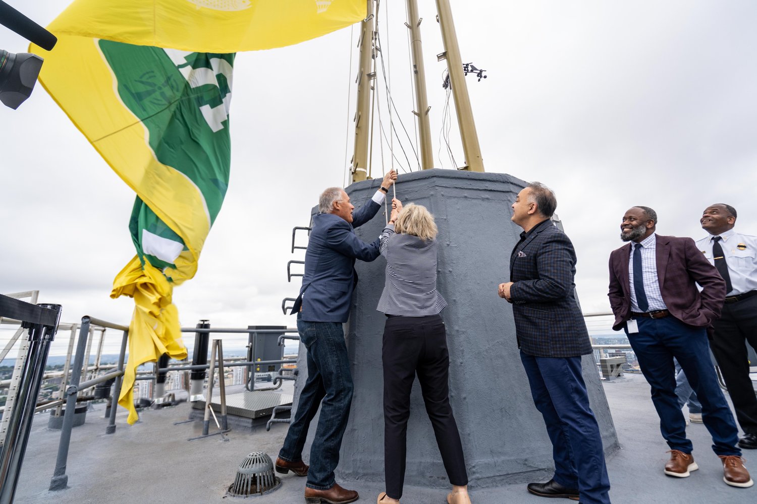 Gov. Jay Inslee raises a flag on the Space Needle Wednesday.