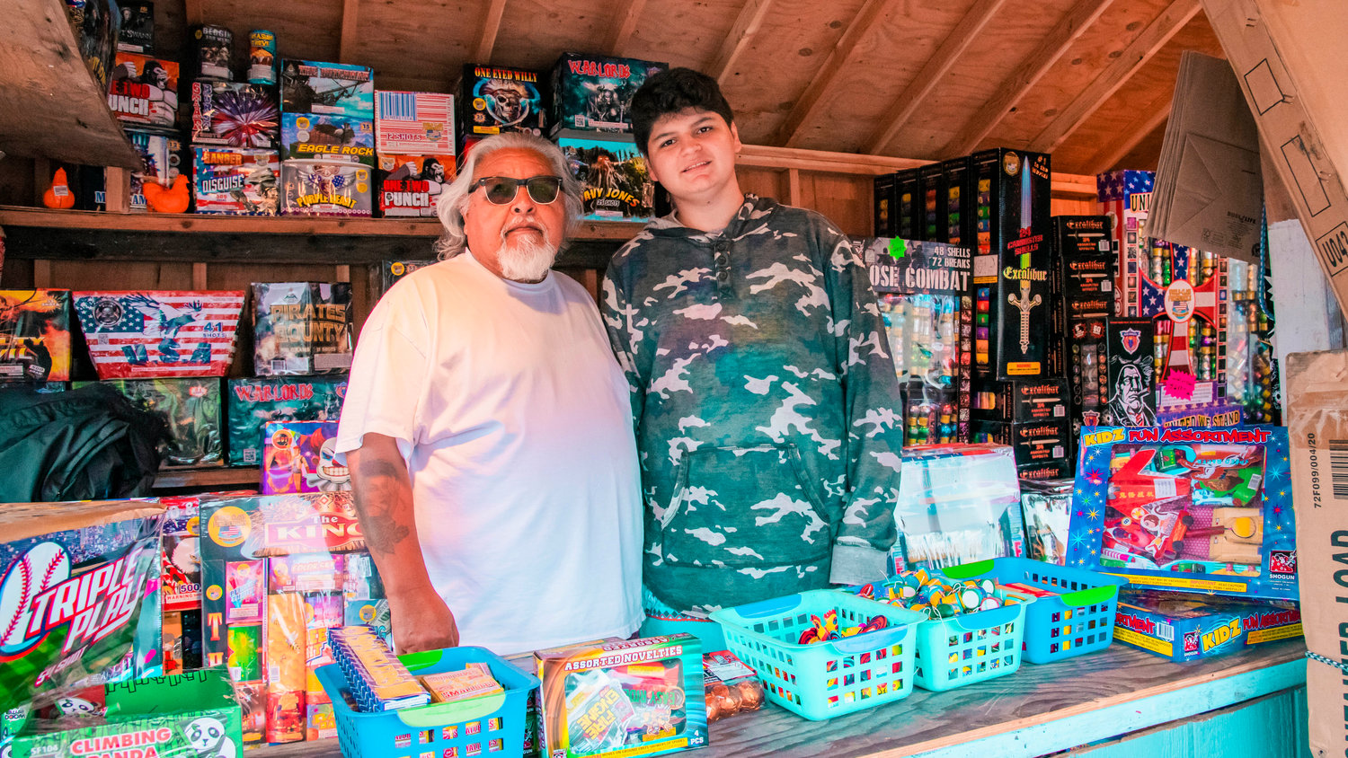 Ray and Artie Romero pose for a photo inside their fireworks booth Thursday. Ray says he hopes one day Artie will take over the business for him.
