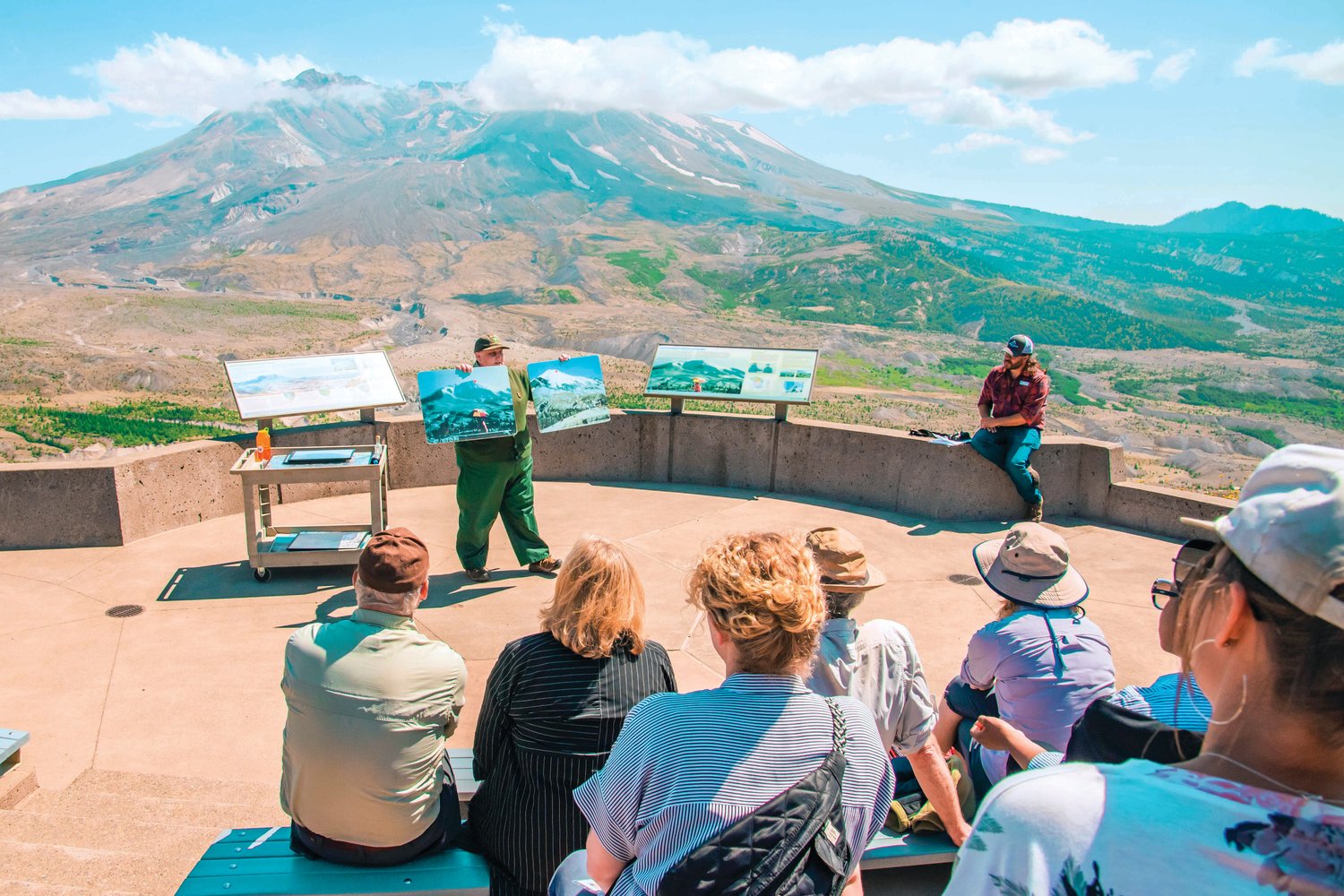 Katie Akers talks about the eruption of Mount St. Helens with Gov. Jay Inslee and Bill Nye in attendance at an outdoor auditorium Thursday at the Johnston Ridge Observatoy.