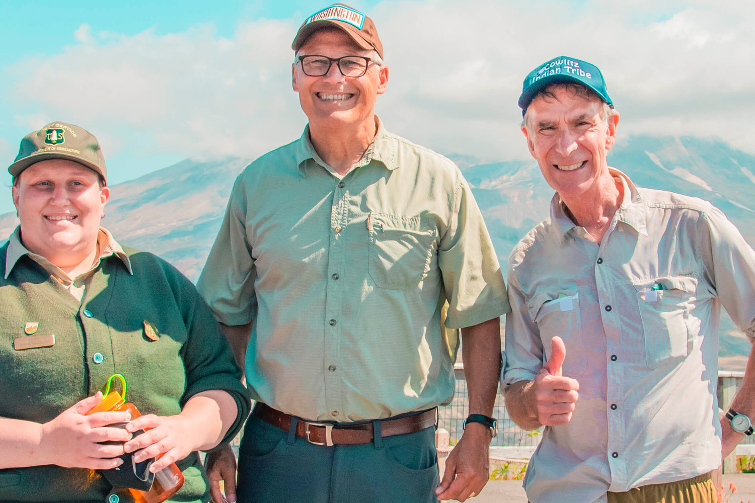 Mount St. Helens sets the backdrop as Katie Akers with the Forest Service, Gov. Jay Inslee, and Bill Nye pose for a photo along a trail Thursday outside the Johnston Ridge Observatoy.