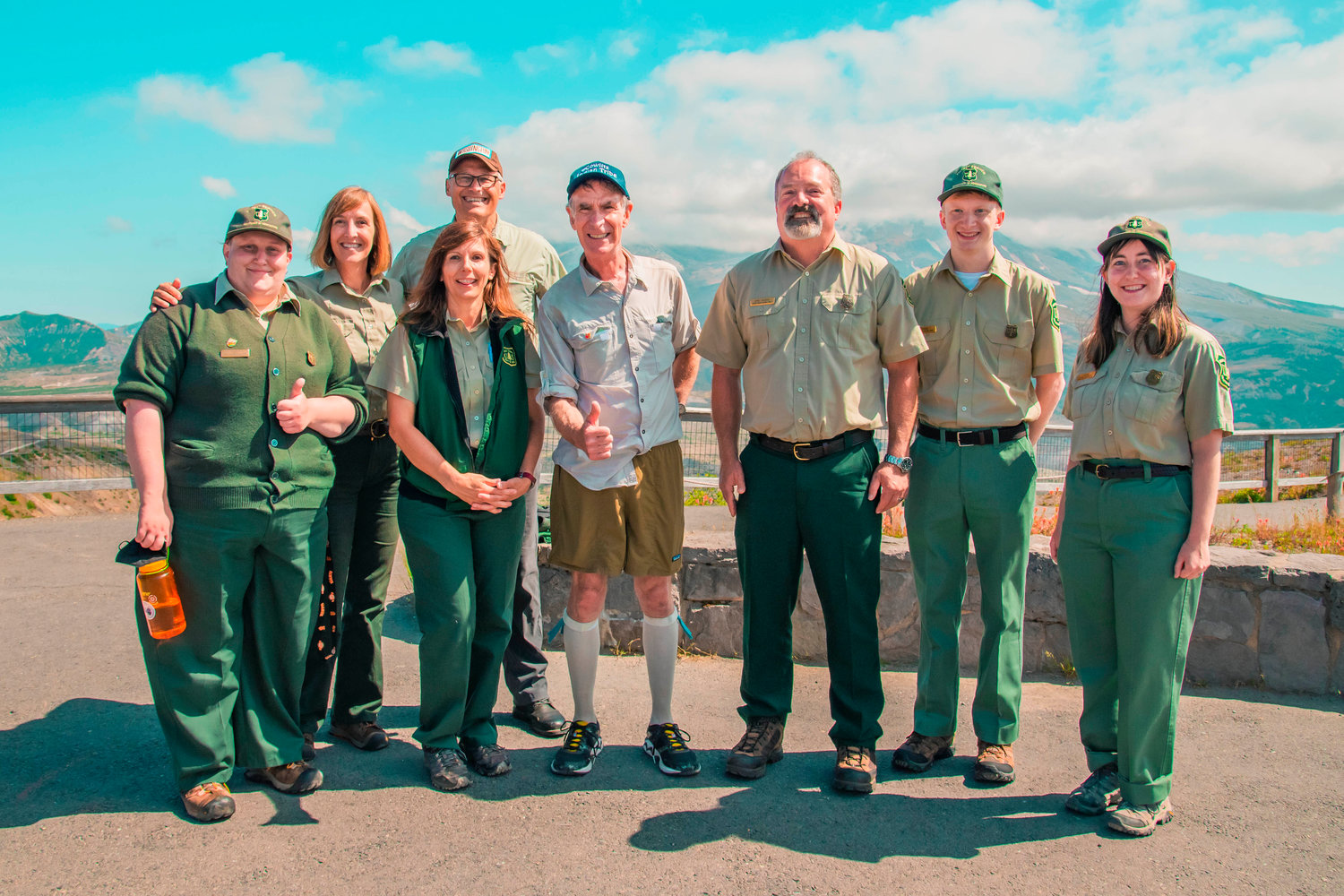Members of the U.S. Forest Service pose for a photo with Gov. Jay Inslee and Bill Nye in front of Mount St. Helens during a visit to Jonhston Ridge.