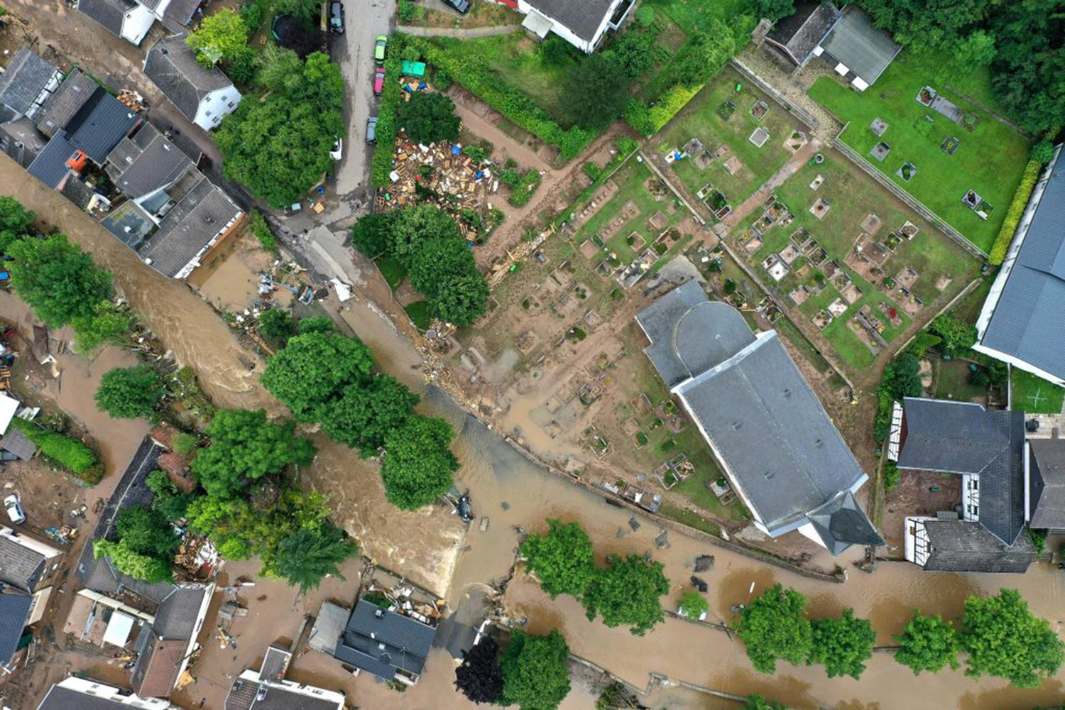 An aerial view taken on July 16, 2021 shows a flooded area with a church and a cemetery nerby in Iversheim near Bad Muenstereifel, western Germany, after heavy rain hit parts of the country, causing widespread flooding. - The death toll from devastating floods in Europe soared to at least 126 on July 16, most in western Germany where emergency responders were frantically searching for missing people.
