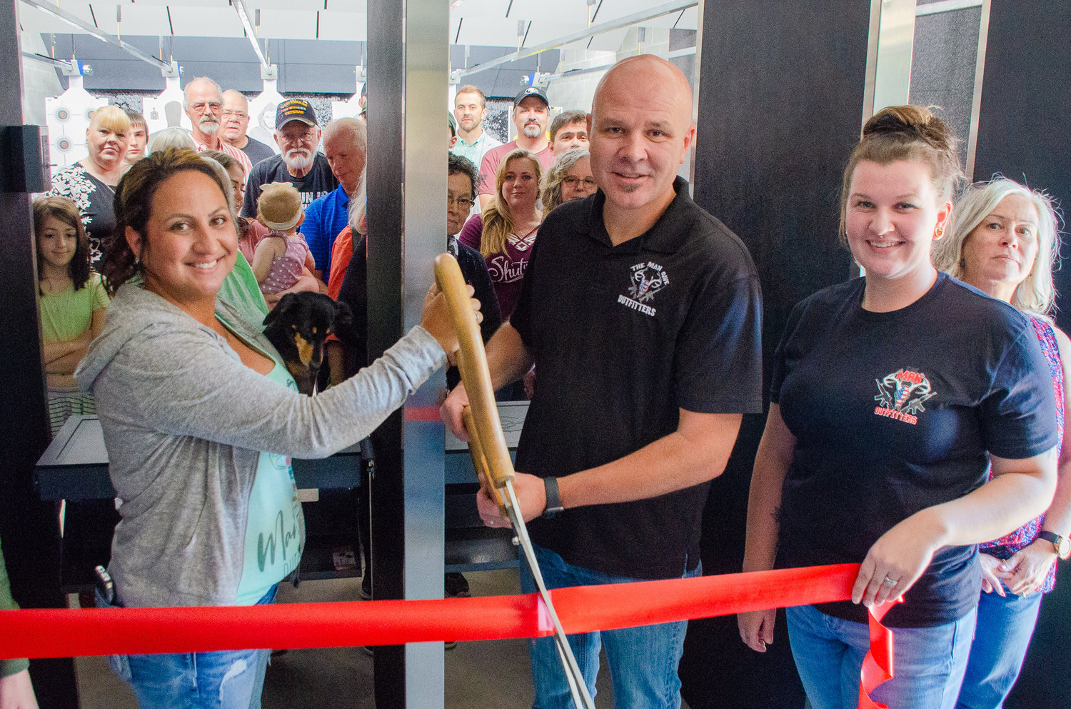 The Man Cave Outfitters co-owners Shoni and Hobe Pannkuk position the Centralia-Chehalis Chamber of Commerce’s giant scissors Monday afternoon during a ribbon-cutting event.