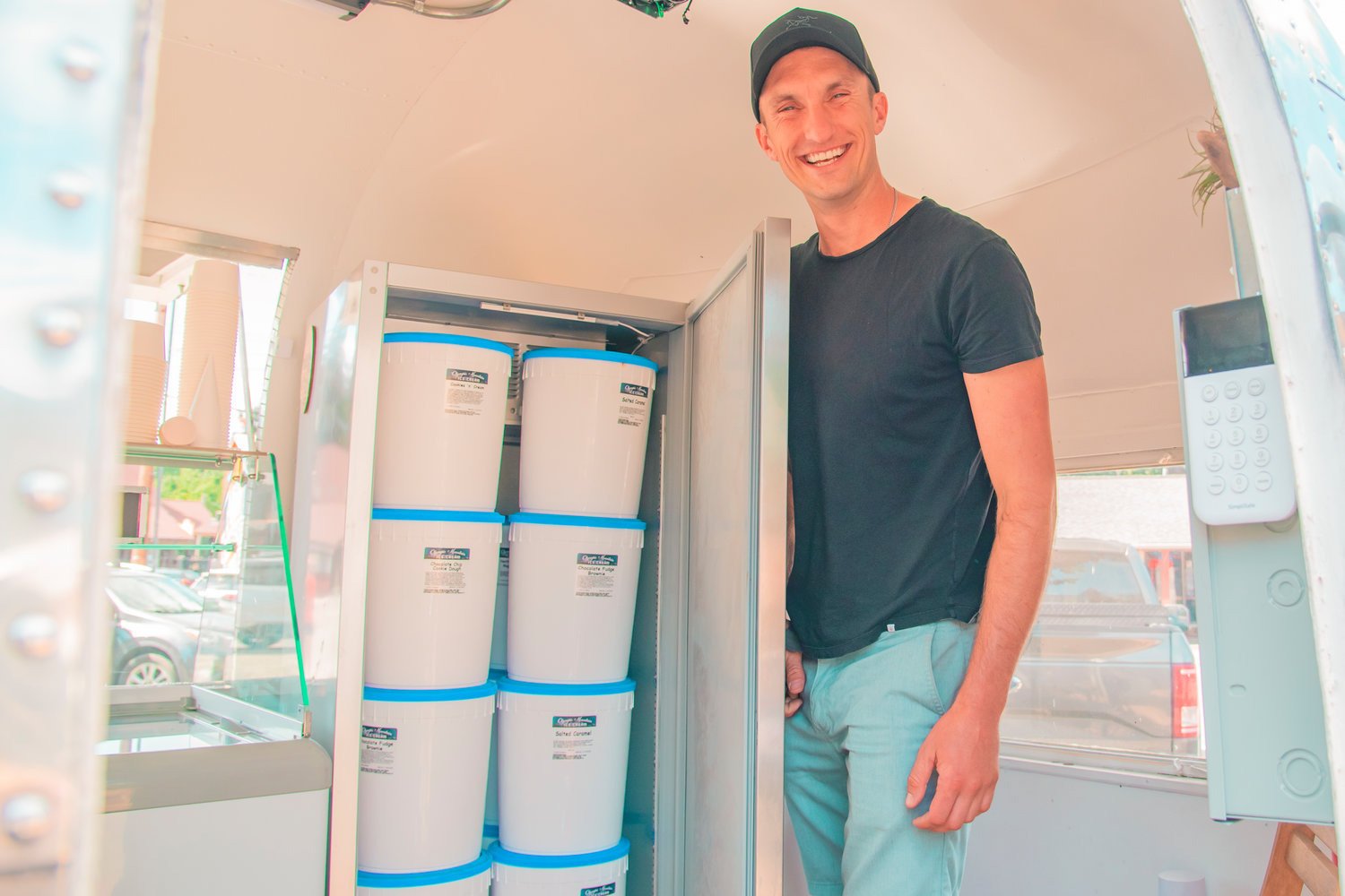 Sean Schwalbe smiles and poses for a photo next to a cooler full of Olympia Mountain Ice Cream next to his Airstream Wednesday in Packwood.