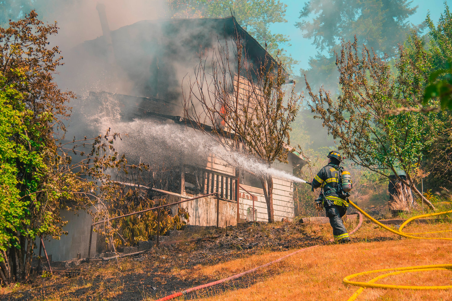 A Riverside Fire Authority firefighter uses a hose to put out flames at a residential structure in Centralia on Thursday.