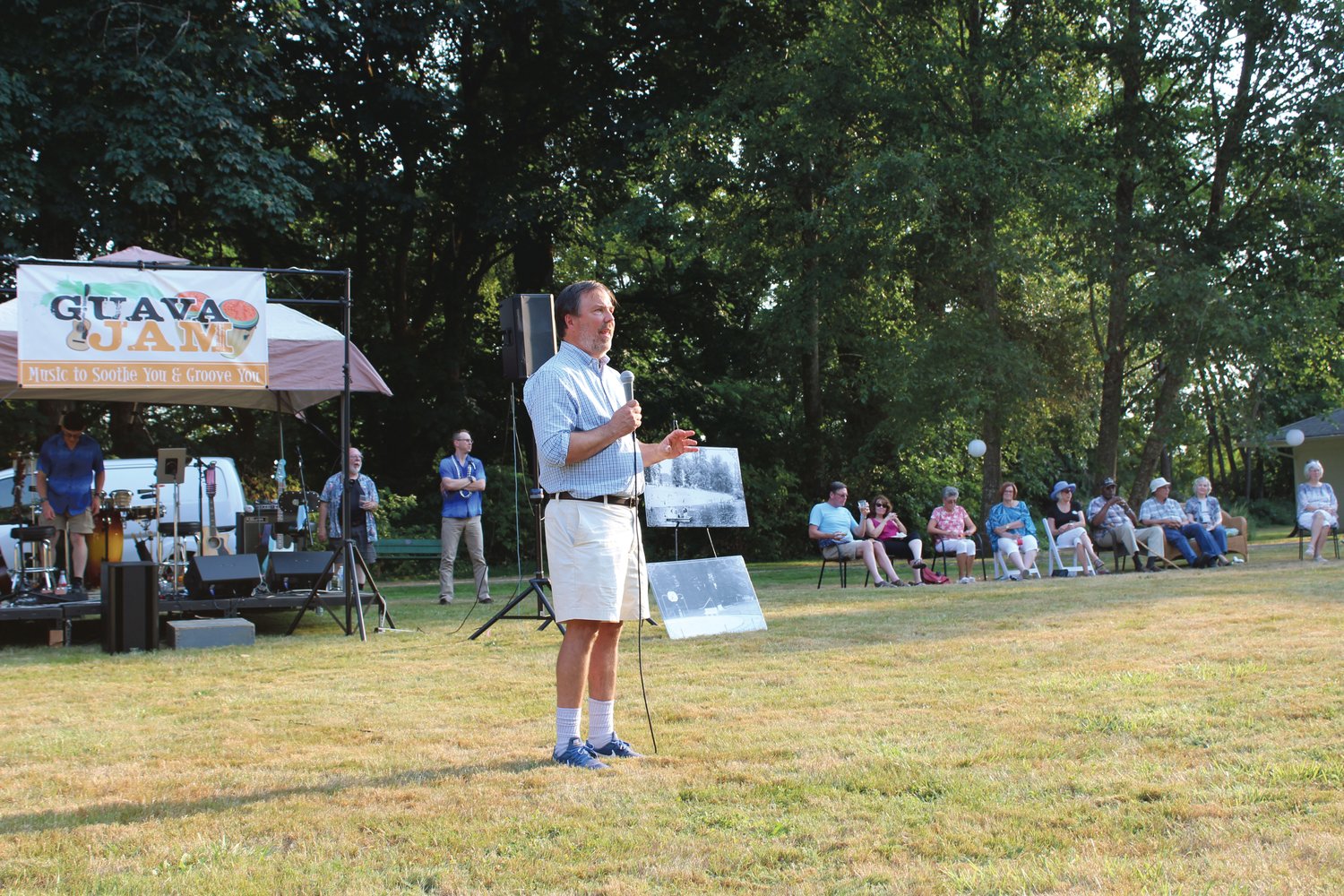 Board Member J. Vander Stoep addresses the crowd at the Chehalis Foundation's Party in the Park fundraiser for Lintott-Alexander Park. Behind him are historic photos of the park, which was deeded to the City of Chehalis in the early 1900s, that the Chehalis Foundation board was given by the Lewis County Historical Museum.