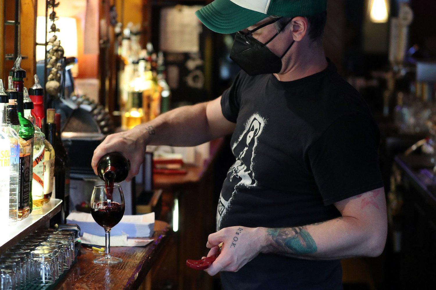 Jon Acosta pours a glass of wine for a customer at Four Moon Tavern in Chicago on July 29, 2021. After a positive COVID-19 test amongst its staff, Four Moon Tavern now requires customers to wear face masks and proof of vaccine for anyone who wants to sit at the bar. (Terrence Antonio James/Chicago Tribune/TNS)