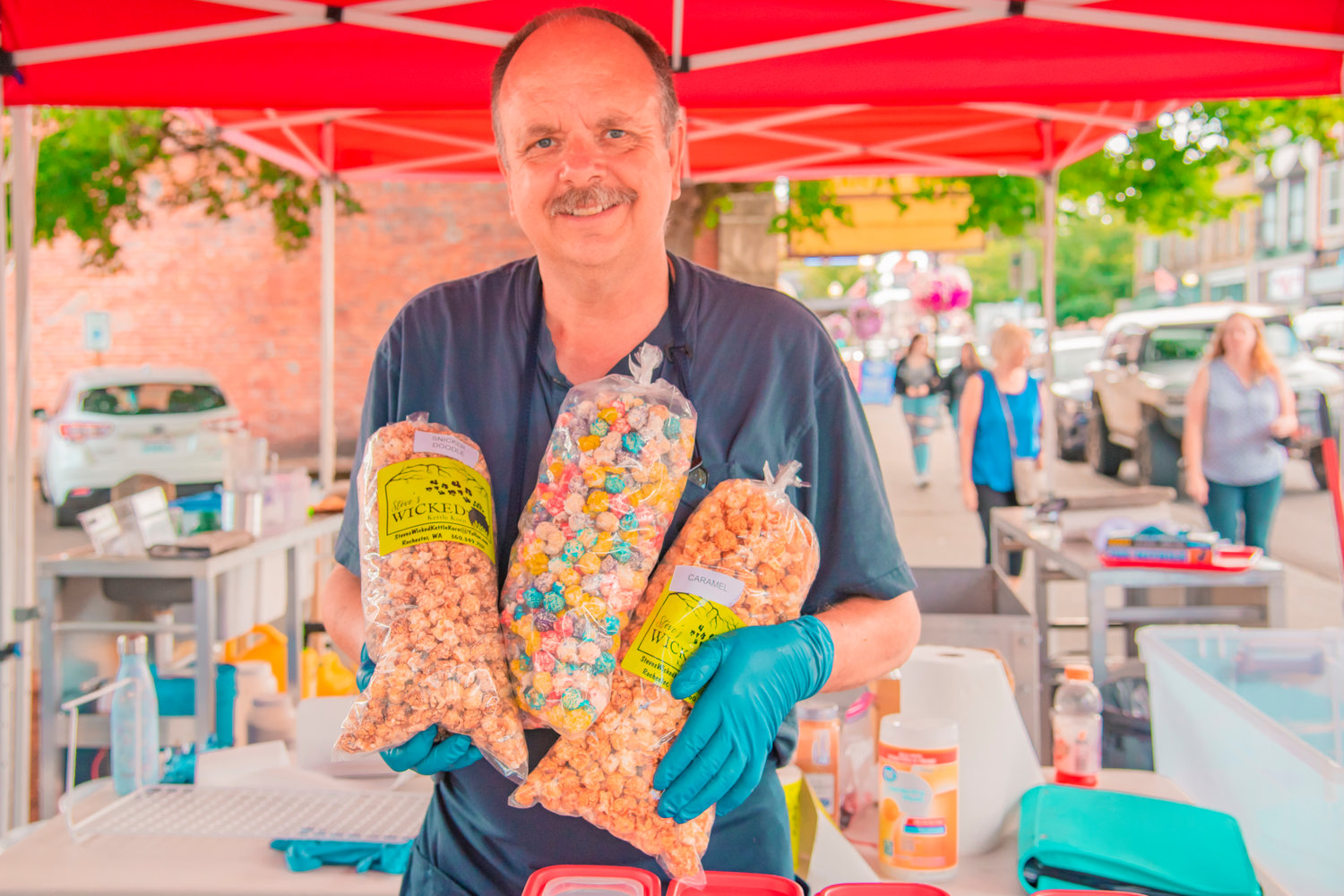 Steve Smythe, of Steve's Wicked Kettle Korn, poses for a photo with bags of flavored popcorn during Antique Fest in downtown Centralia on Friday.