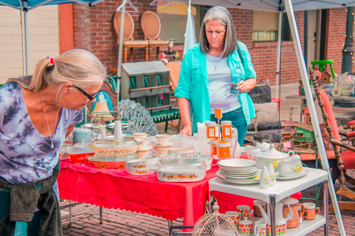 Visitors walk under canopies from different vendors containing a variety of items from tableware to furniture during Antique Fest in downtown Centralia on Friday.