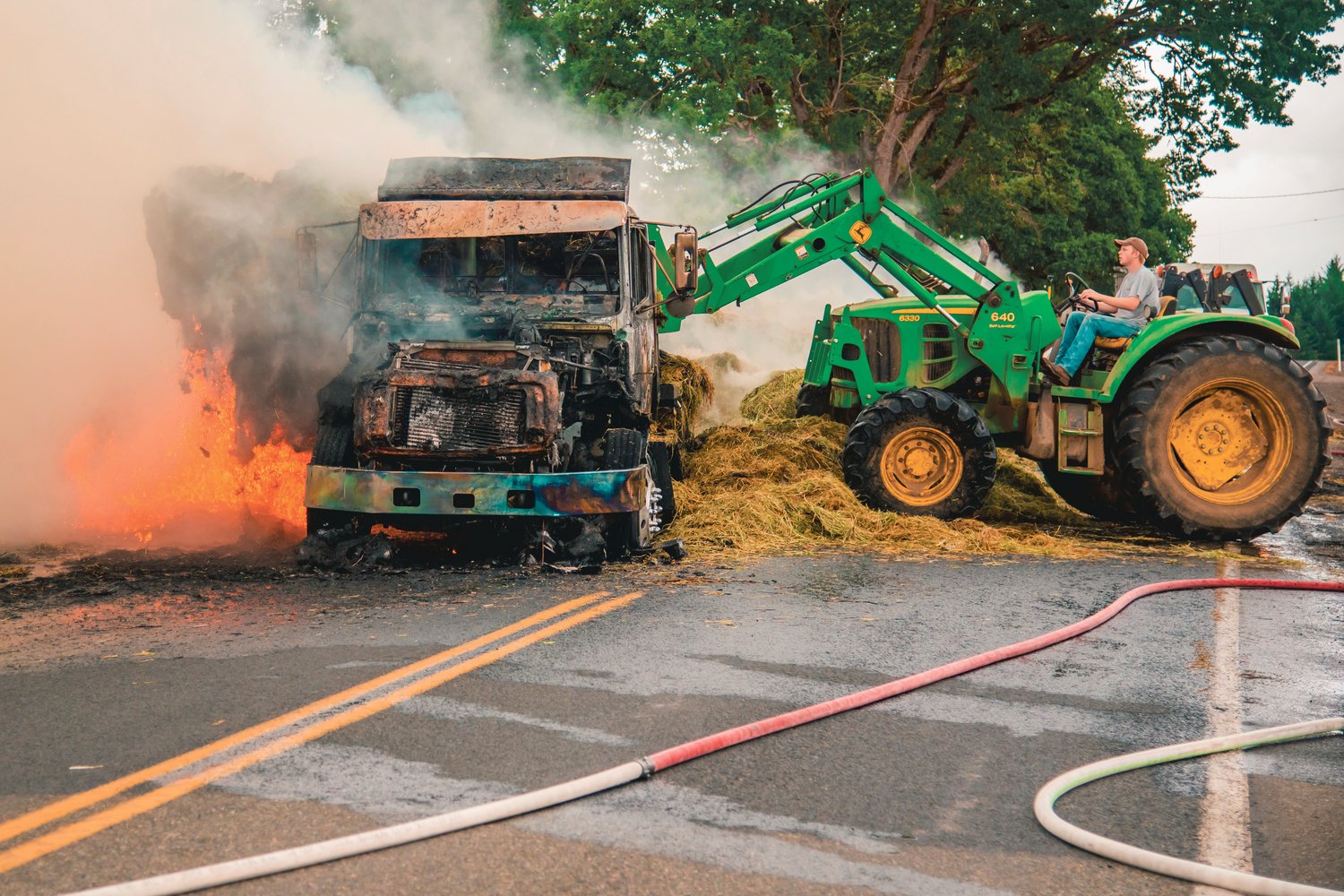 Hay is removed from a truck sparking flames on Highway 603 at the intersection of Tune Road west of Chehalis on Saturday.