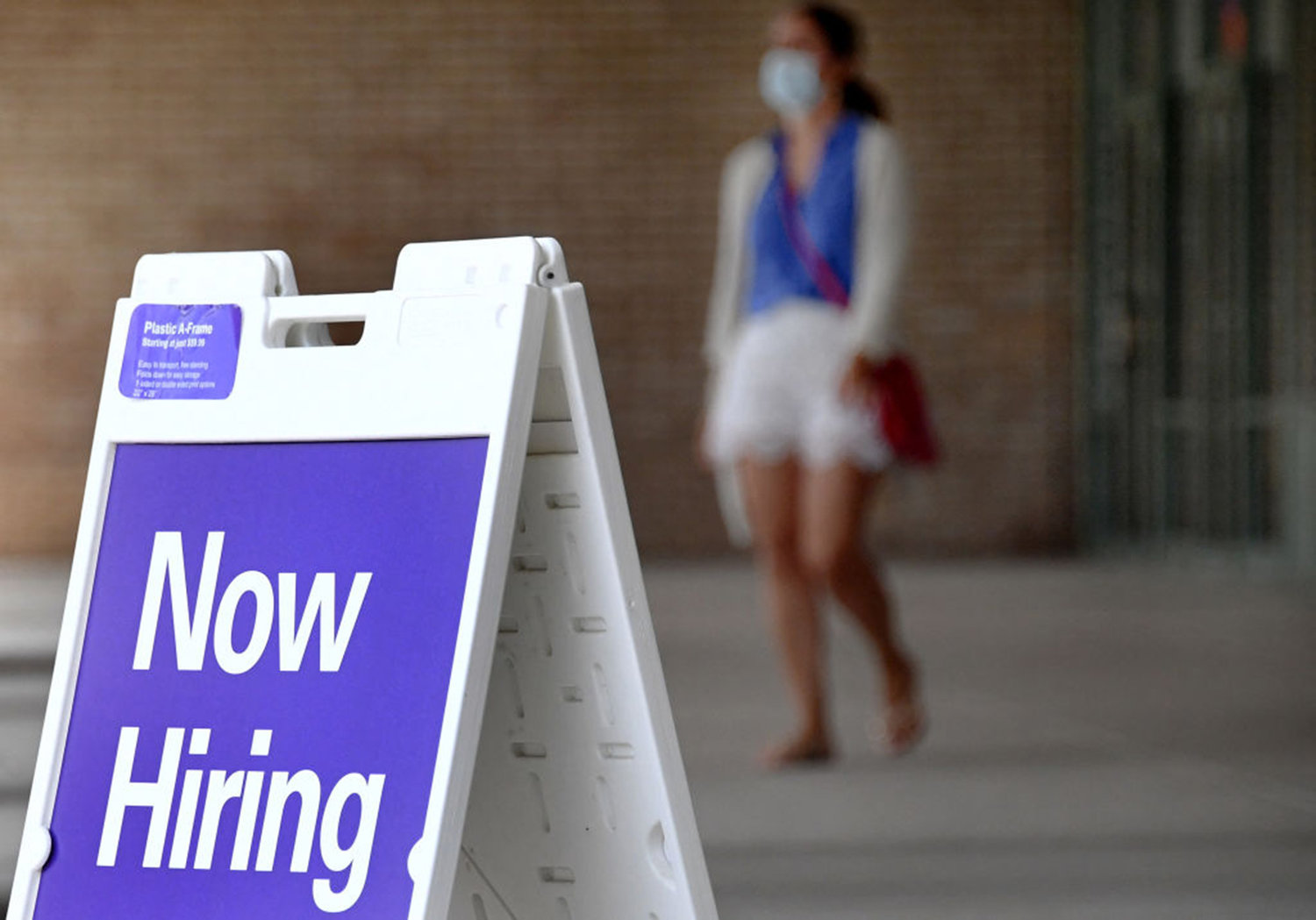 Pedestrians walk by a "Now Hiring" sign outside a store on August 16, 2021 in Arlington, Virginia. (Olivier Douliery/AFP via Getty Images/TNS)