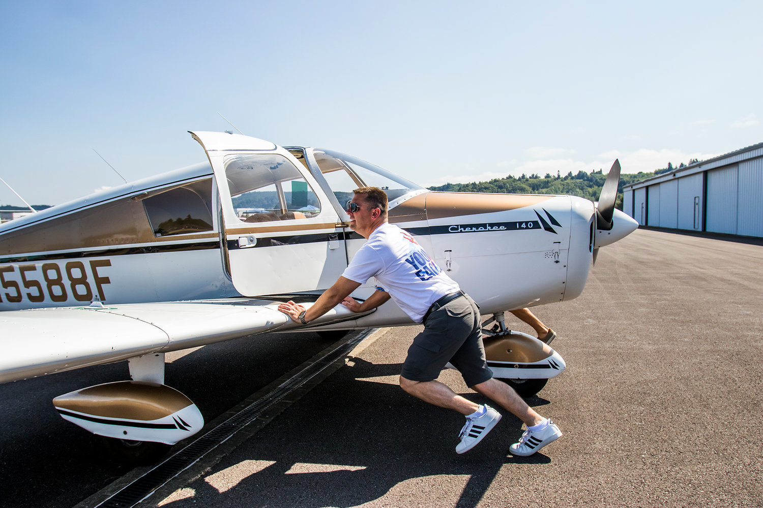 Brandon Rakes, the airport operations manager of the Chehalis-Centralia Airport, pushes his 1968 Piper Cherokee Airplane back into an open spot during the Young Eagles Program in celebration of ChehalisFest.