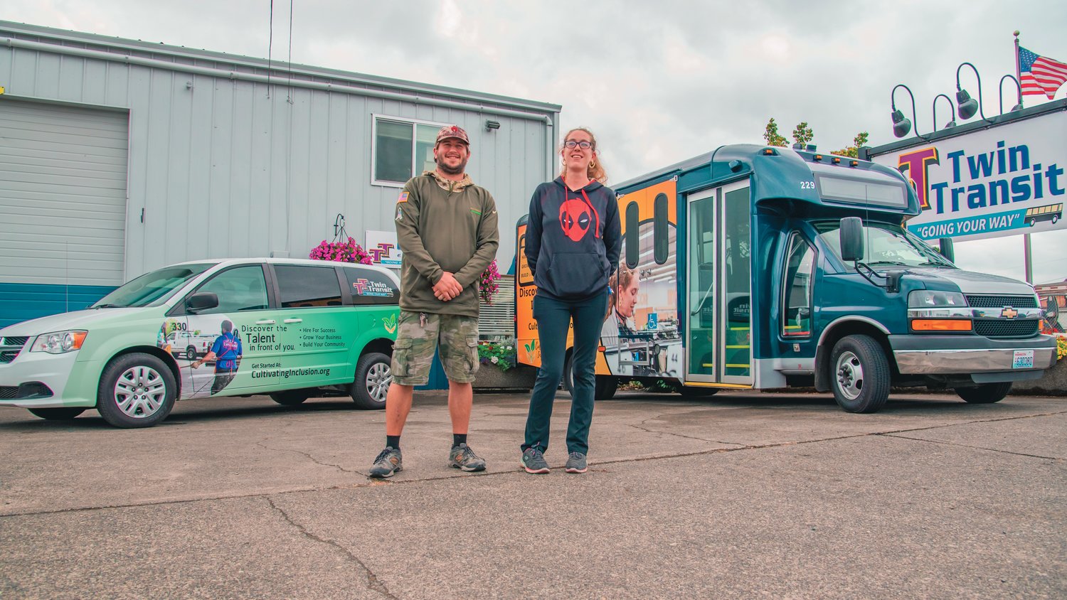 Adrian Rone and Hannah Byrd smile and pose for a photo in front of newly wrapped Twin Transit rides featuring their photos respectively Thursday in Centralia.
