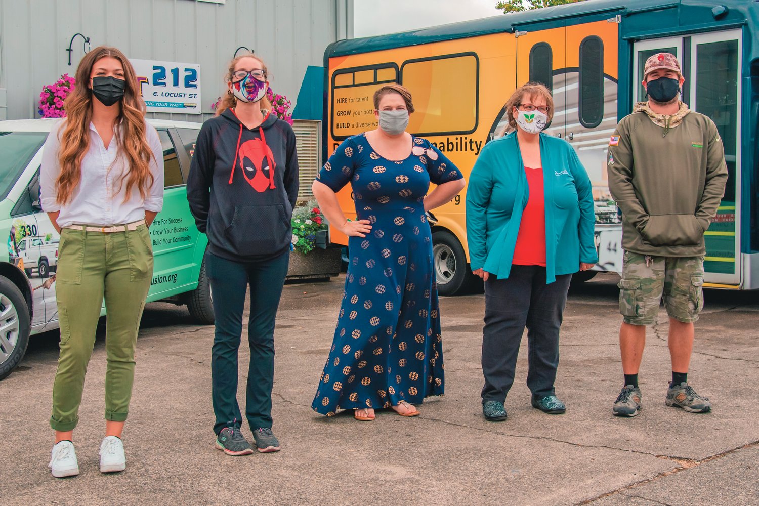 From left, Nicole Miller, Hannah Byrd, Brittany Voie, President of the Lewis County Autism Coalition Lisa Davis and Adrian Rone pose for a photo in front of newly wrapped Twin Transit rides Thursday in Centralia during a Cultivating Inclusion job hiring campaign.