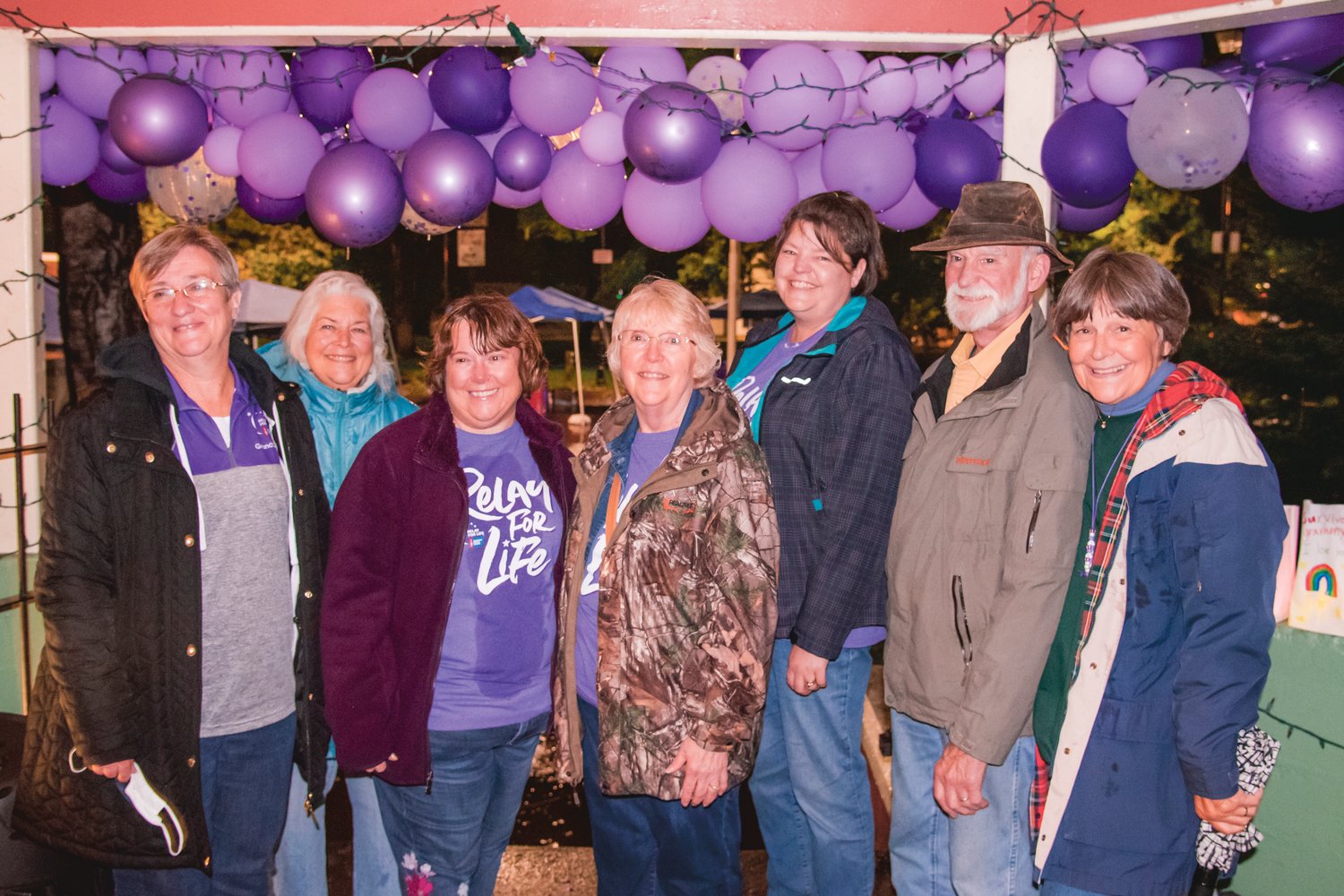 Cancer survivors smile and pose for a photo under the gazebo at George Washington Park during a a Relay For Life event in Centralia Saturday night.
